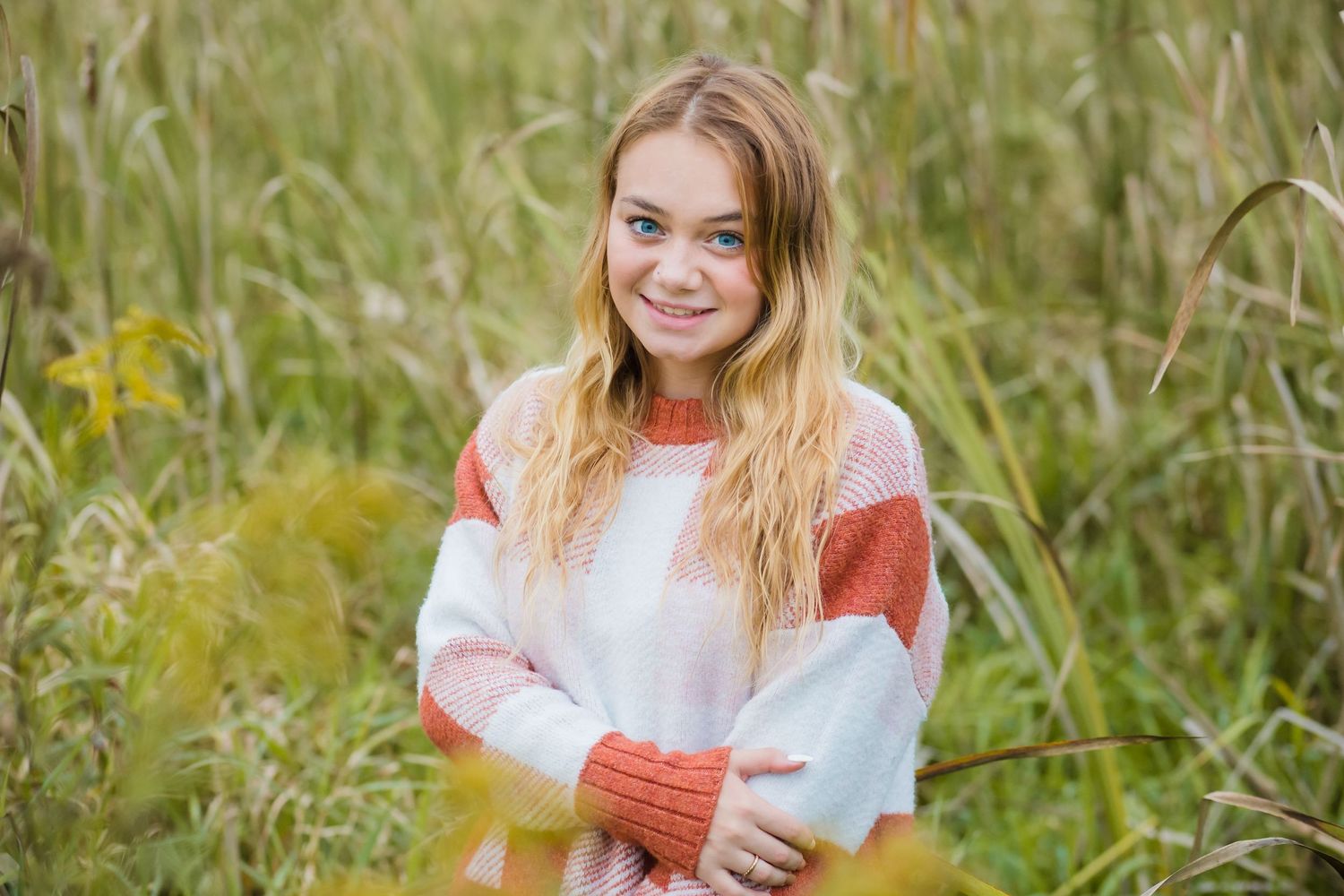 Casual portrait in colorblock sweater standing in tall grass field.
