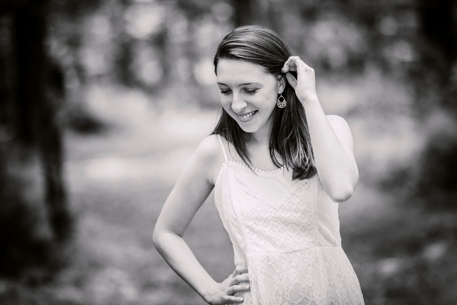 Black and white portrait in a dreamy outdoor setting with soft natural lighting and blurred background.
