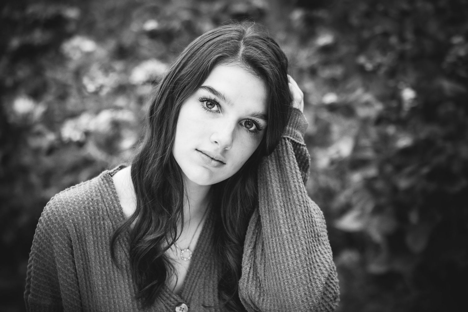 Black and white portrait of person in knit sweater with soft natural background.