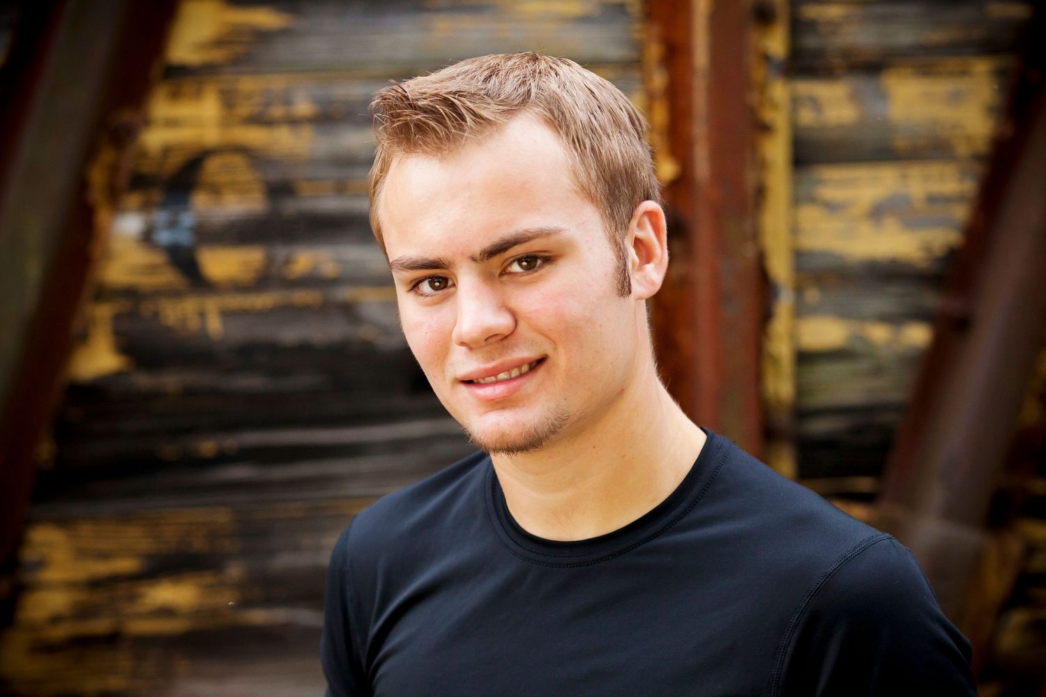 Close-up portrait against rustic wooden background with warm lighting.