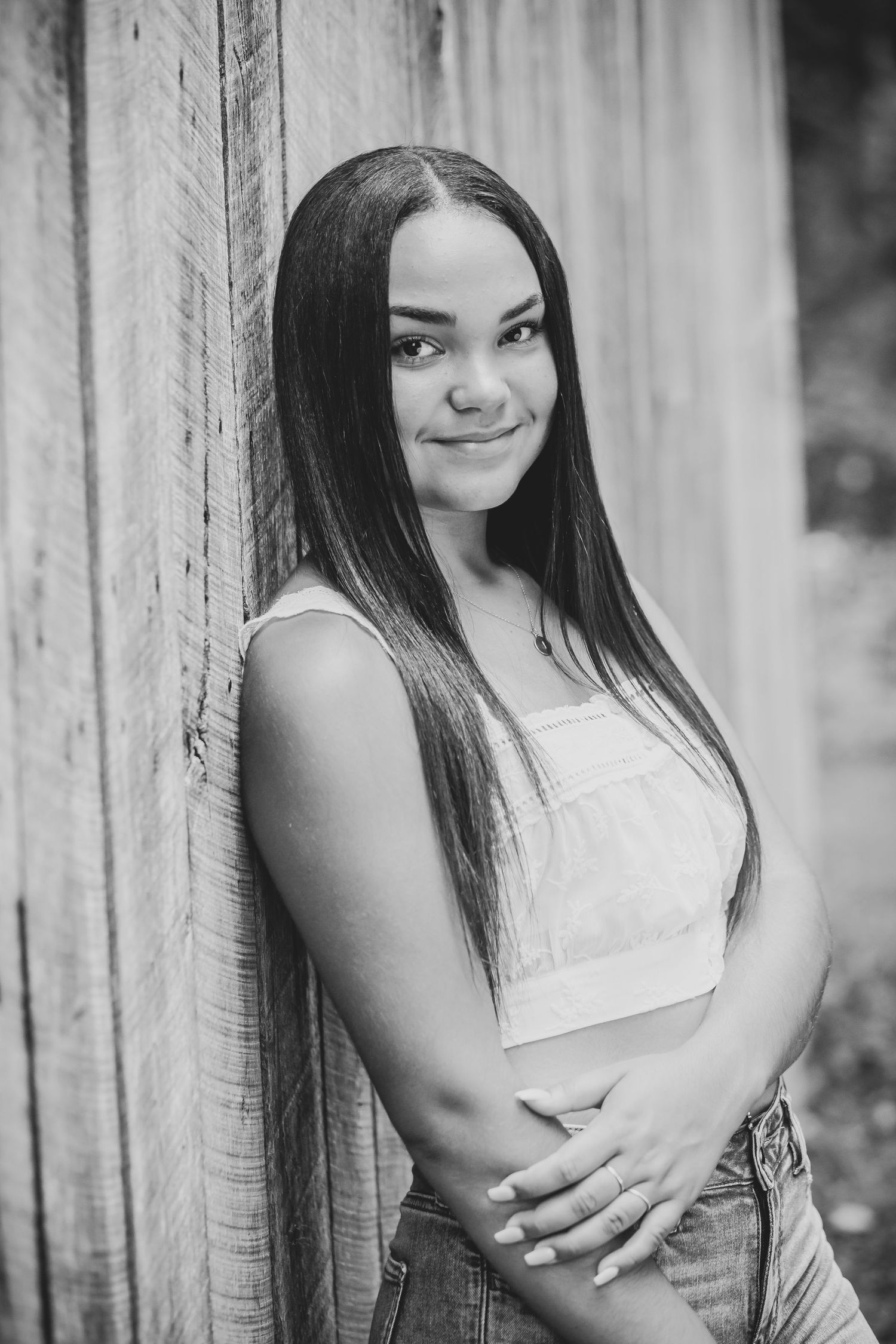 A black and white portrait against a rustic wooden wall backdrop.