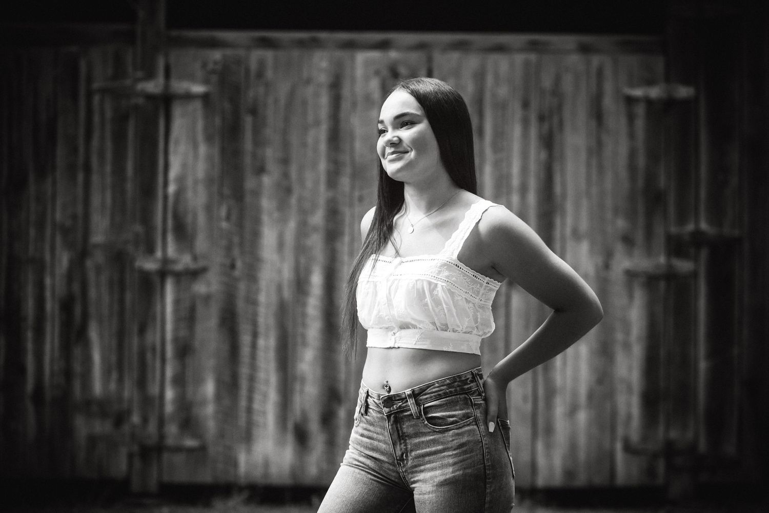 A black and white casual portrait in front of a weathered barn door.