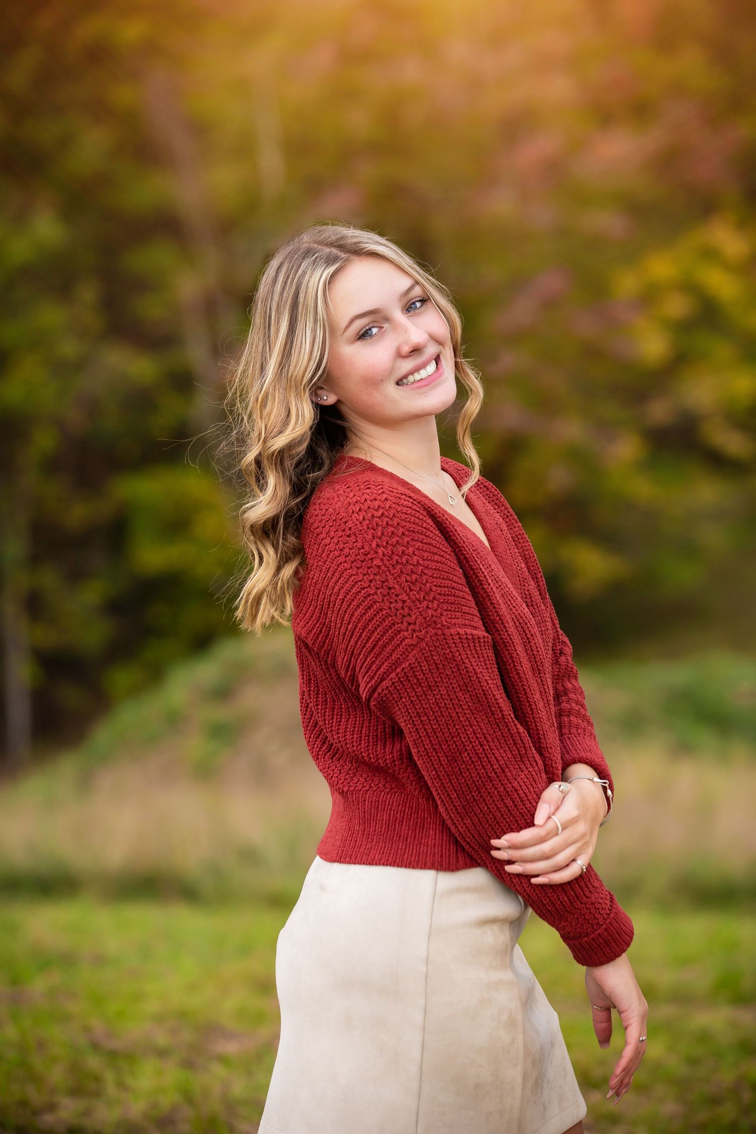 Fall portrait of a person wearing a red knit sweater and beige skirt outdoors.