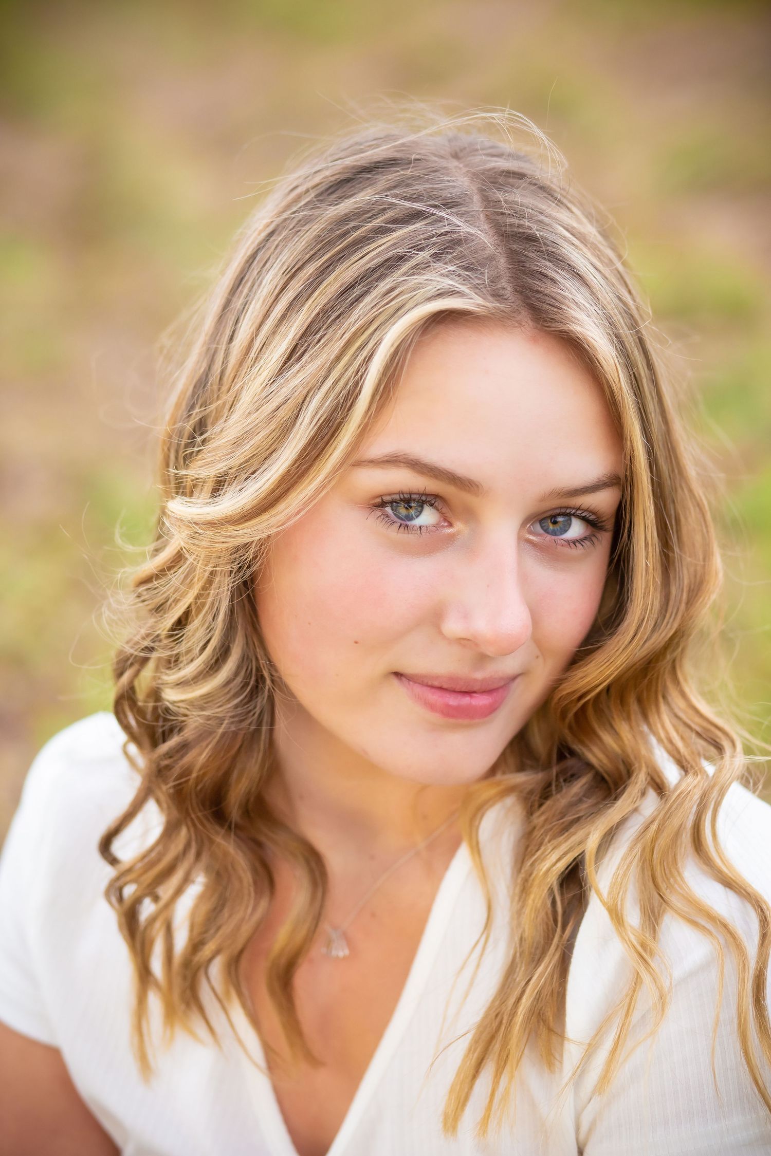 Close-up outdoor portrait with soft natural lighting and wavy blonde hair.