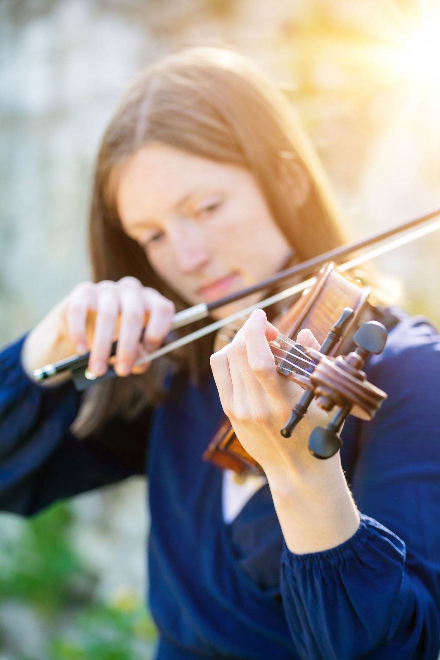 Close-up of violinist playing instrument in soft golden light.