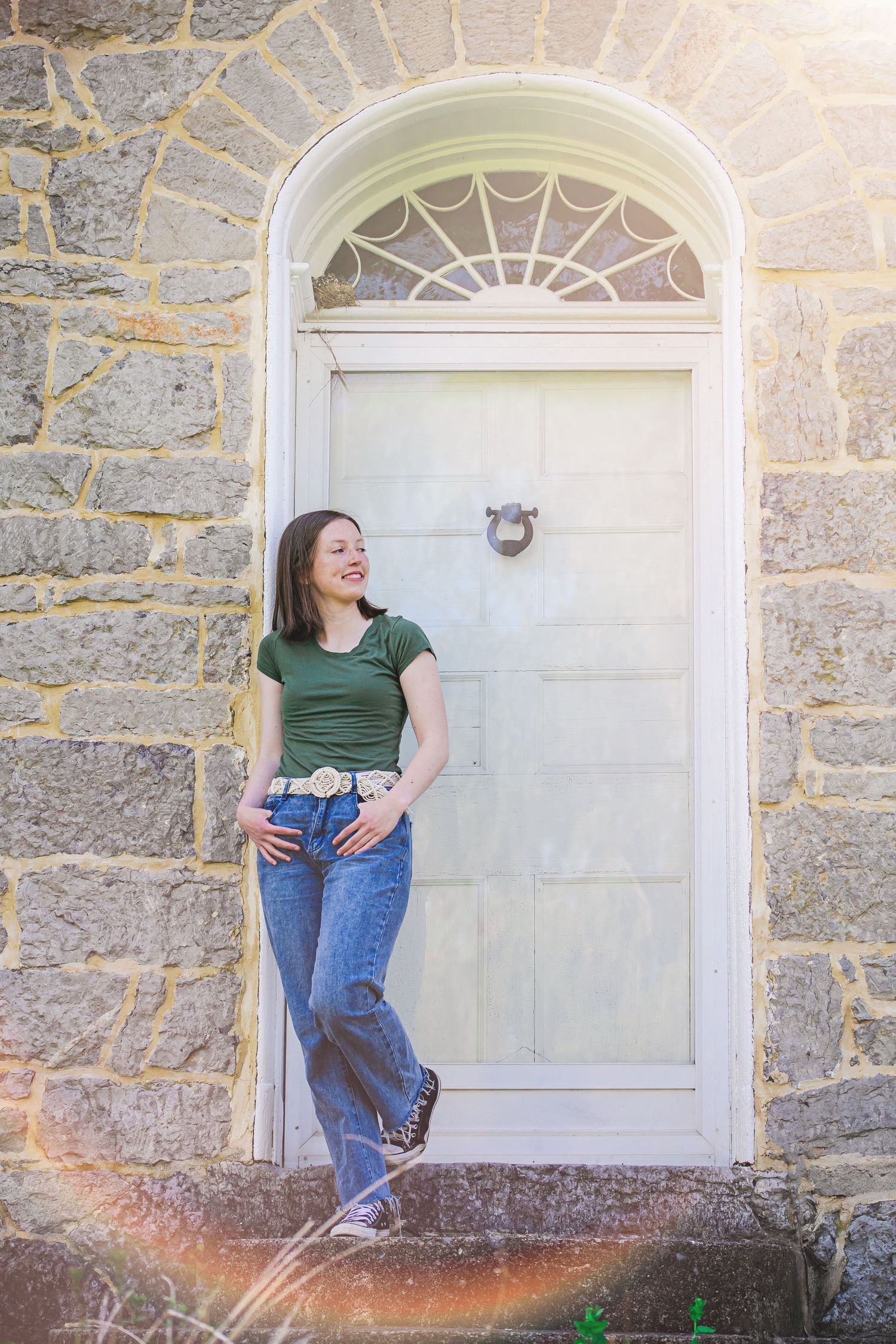 Casual portrait of person standing in front of white arched doorway with stone walls.