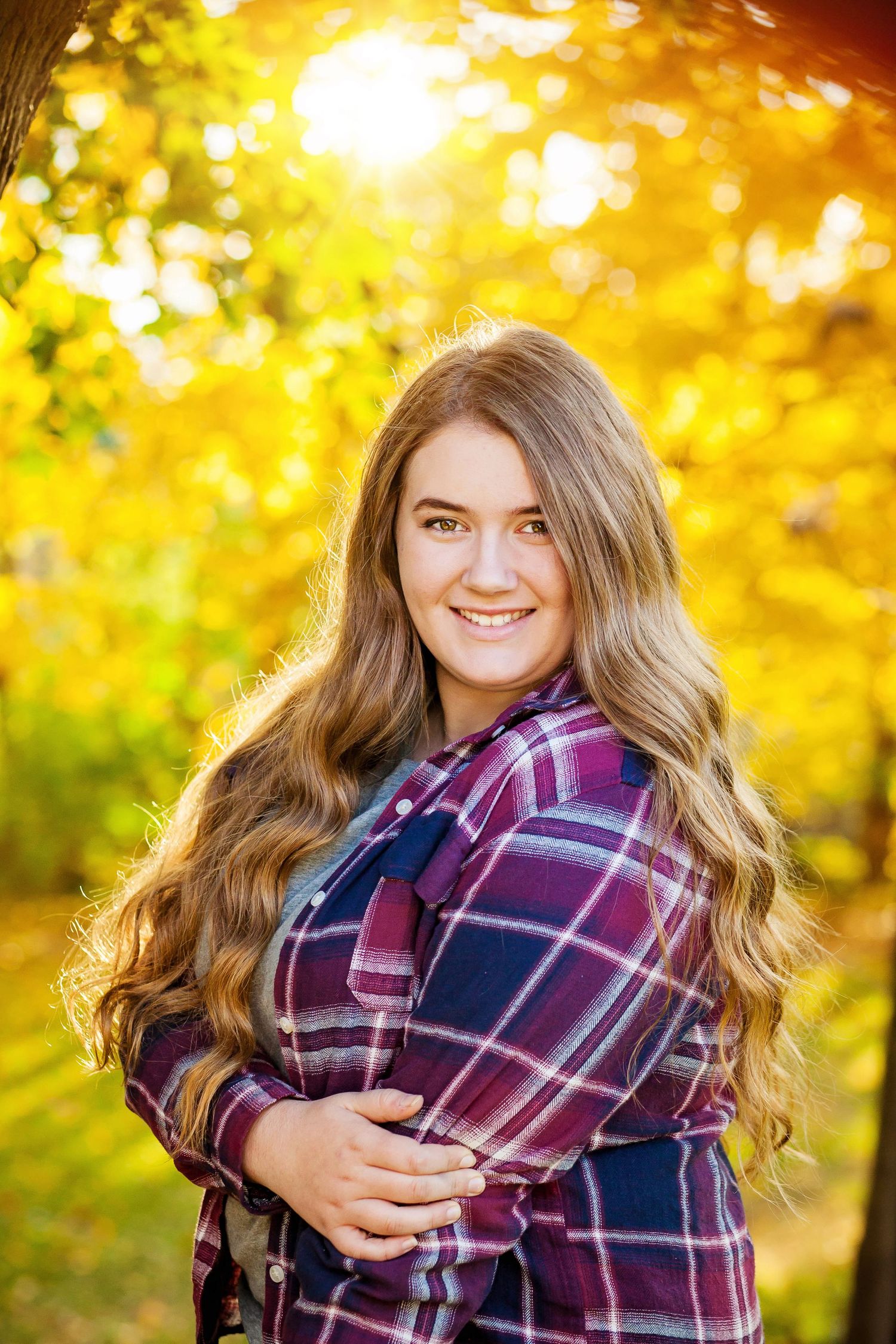 Outdoor portrait in plaid flannel shirt with wavy hair against warm autumn colors.