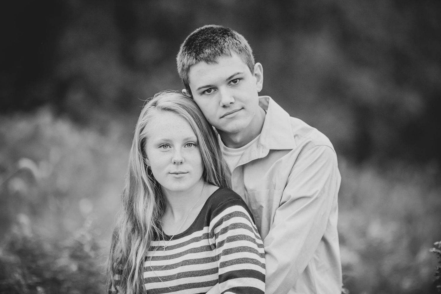 Black and white portrait of a couple in casual attire outdoors.