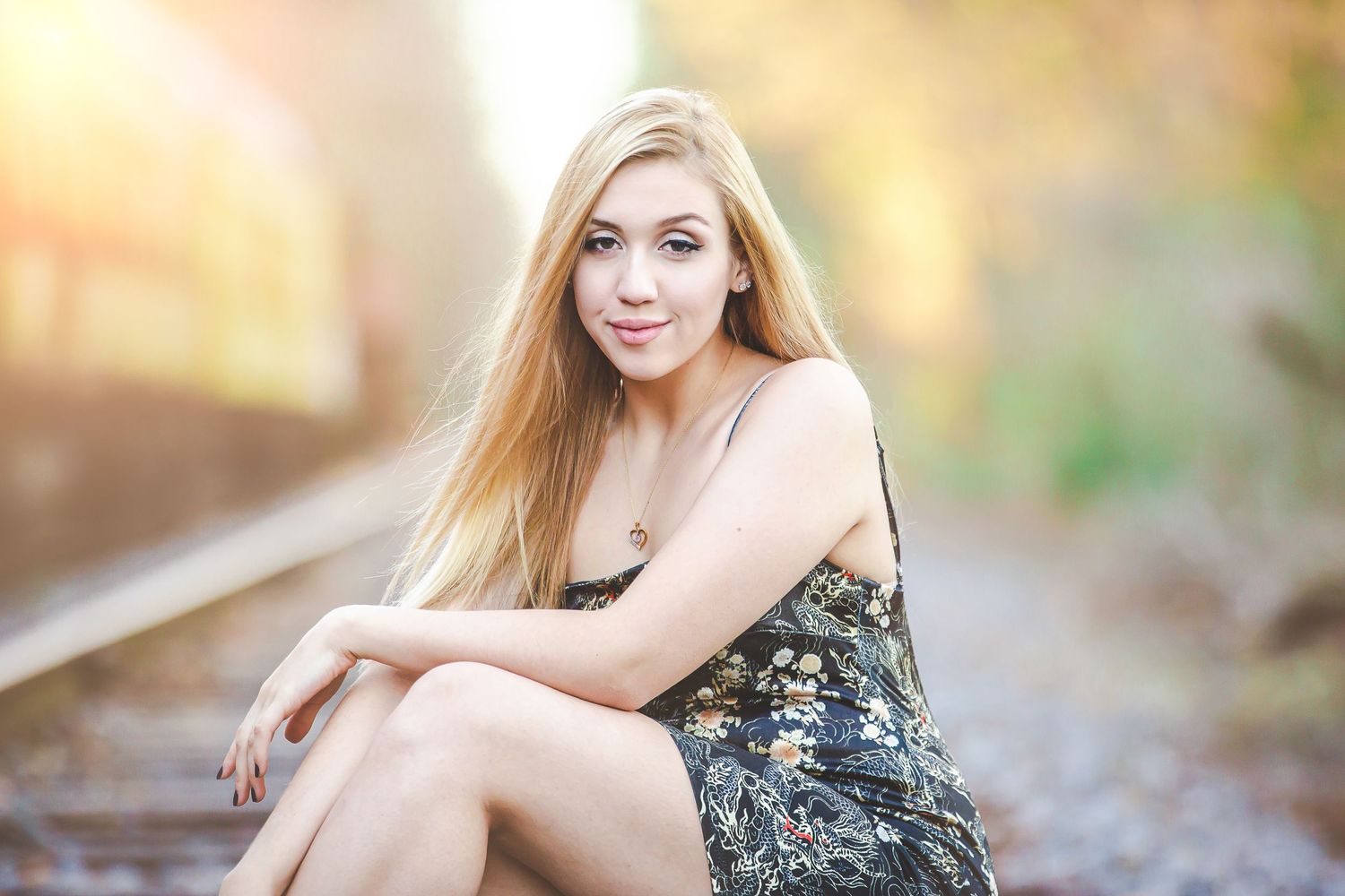 Summer portrait on railroad tracks wearing floral dress in soft evening light.
