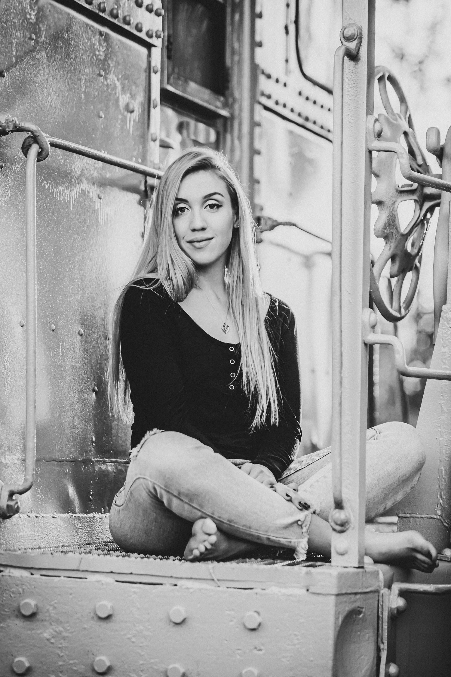 Black and white portrait on industrial metal background wearing casual black top.