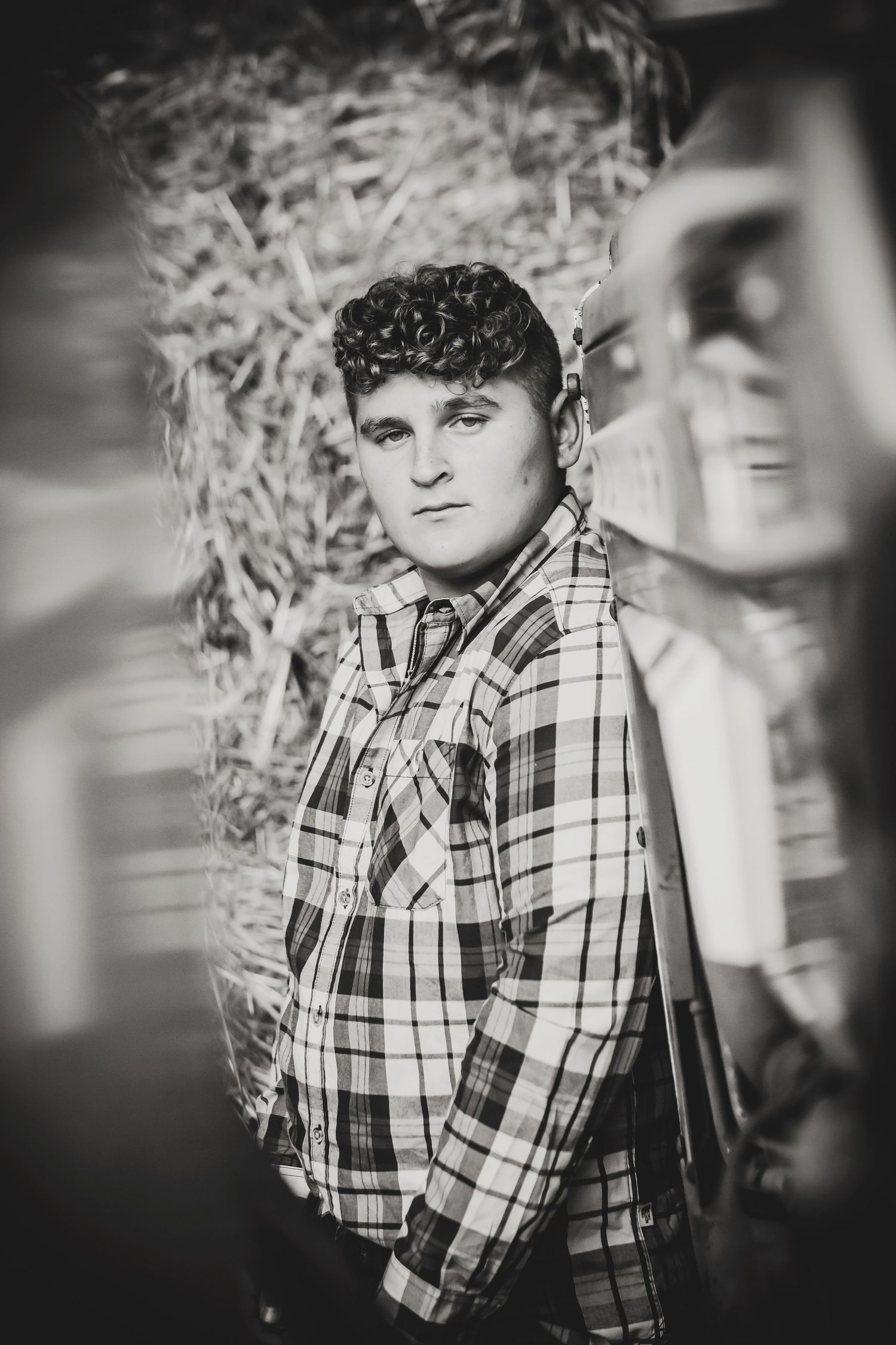 Black and white portrait of someone wearing a plaid shirt against a textured background.