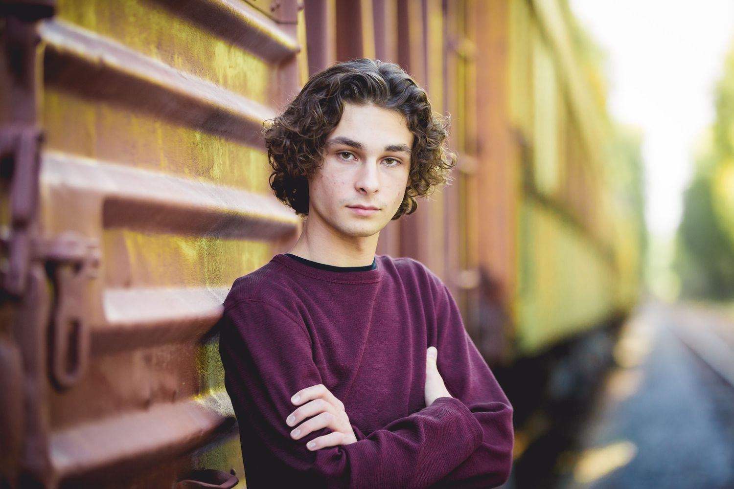 Portrait shot against a vintage train car in warm evening light.