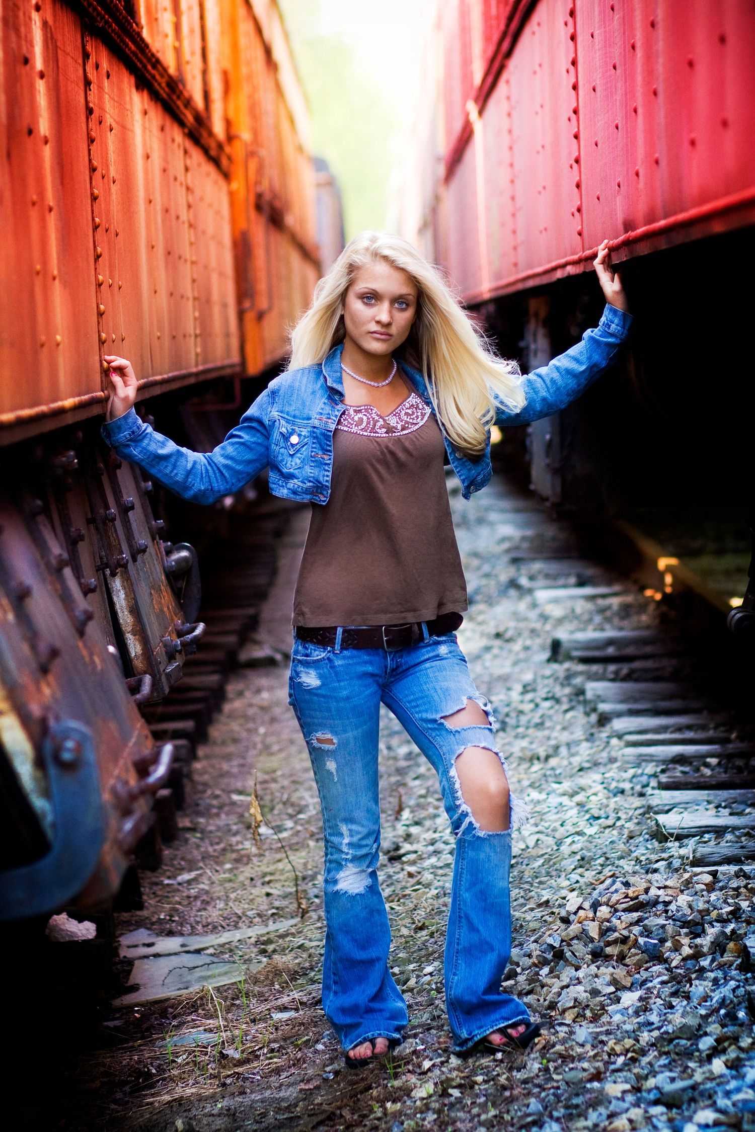 Creative portrait between colorful train cars on railroad tracks.