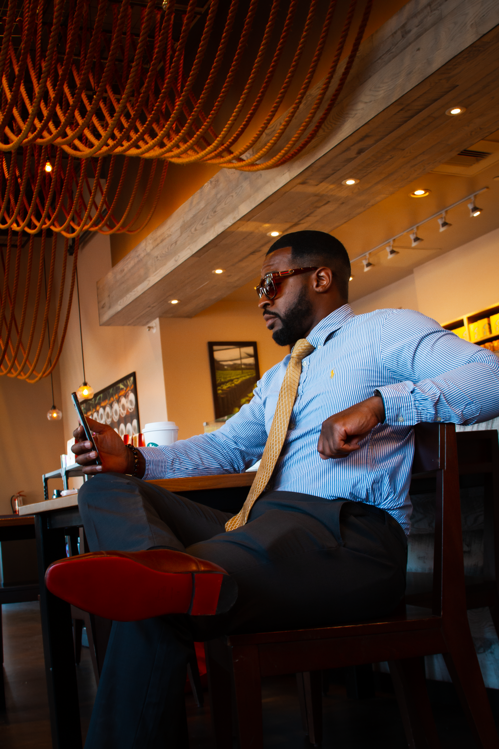 Person lounging in modern restaurant with decorative wooden ceiling and ambient lighting.  L Visions Photography