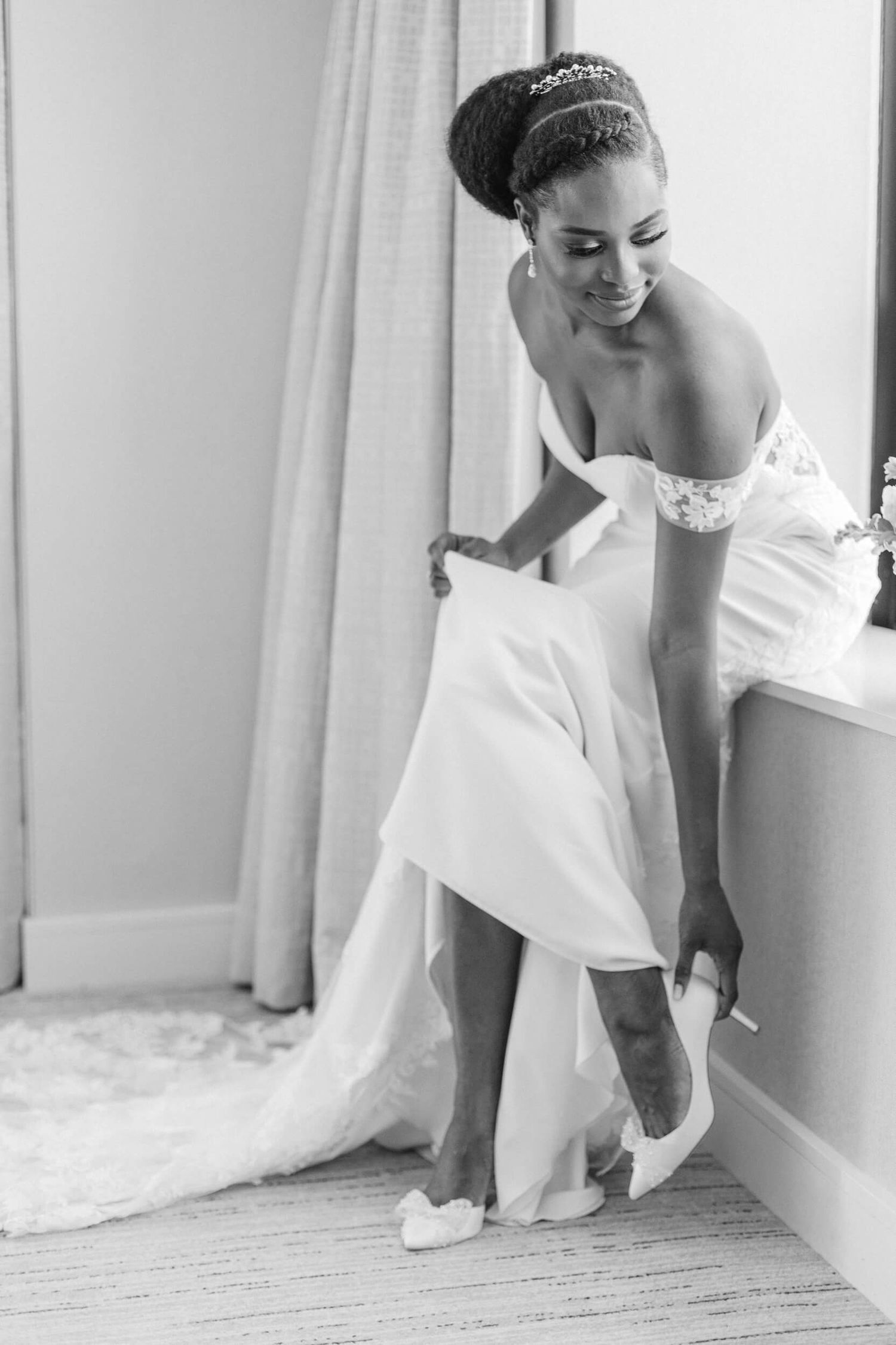 Black and white photo of a bride putting on her shoes before the ceremony.
