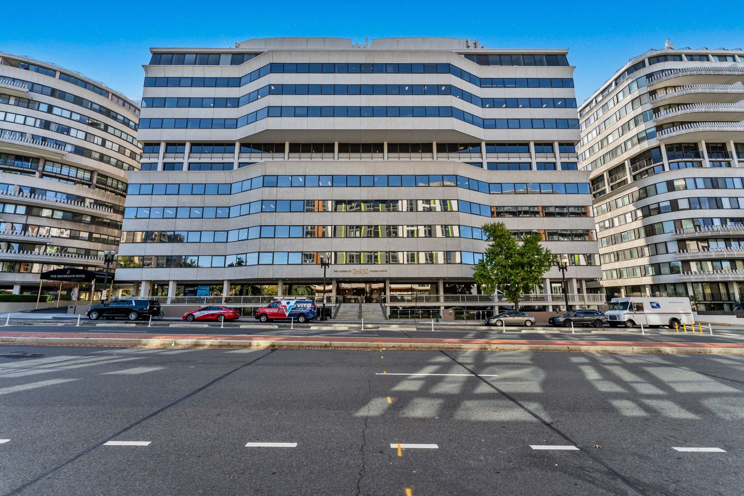 Modern office building complex with curved architecture and striped facade in an urban setting.