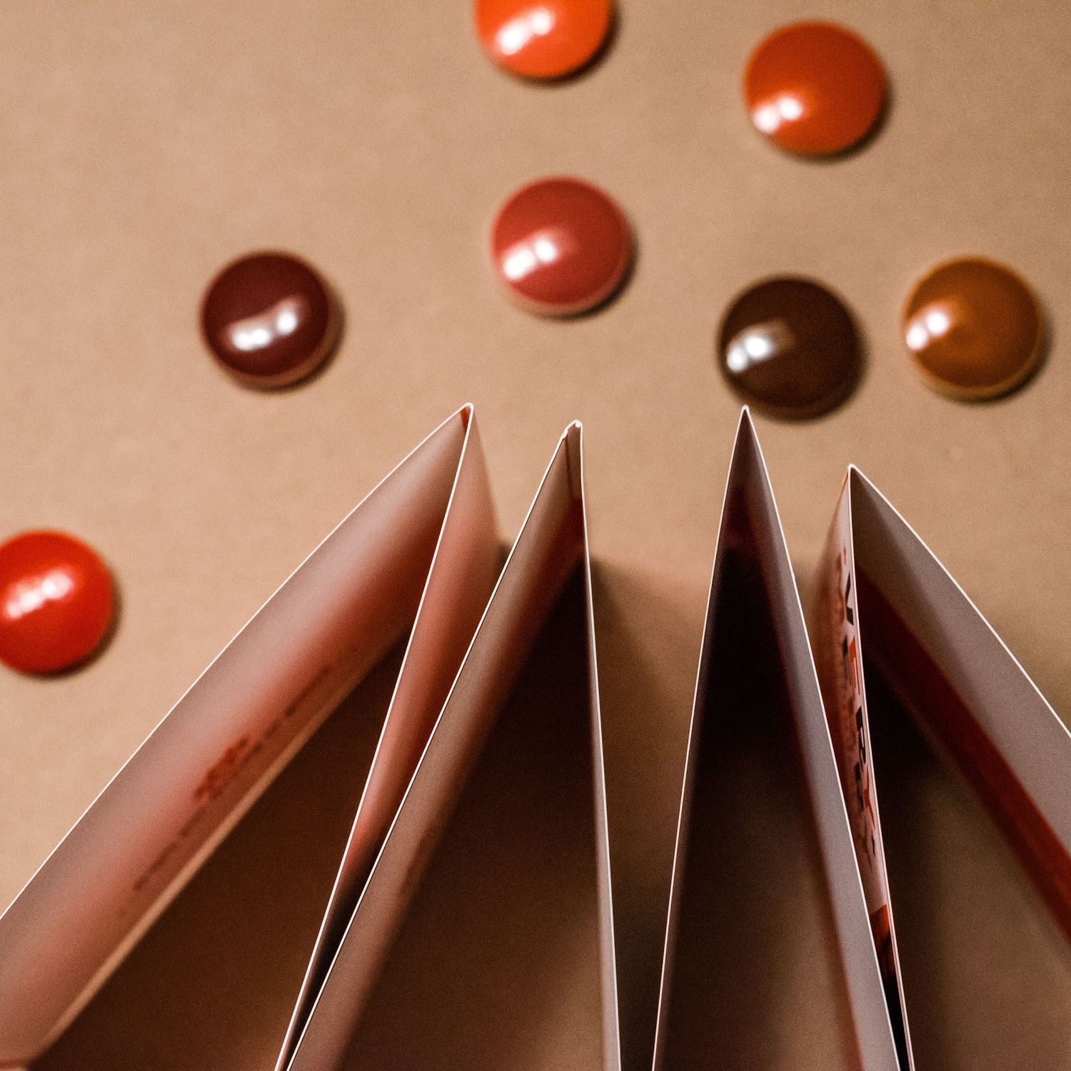 Close-up of brown and reddish circular button pins arranged on a beige surface.