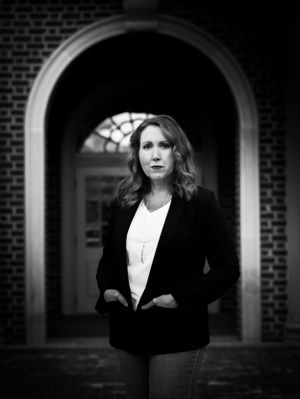 Professional portrait taken under a brick archway in black and white.