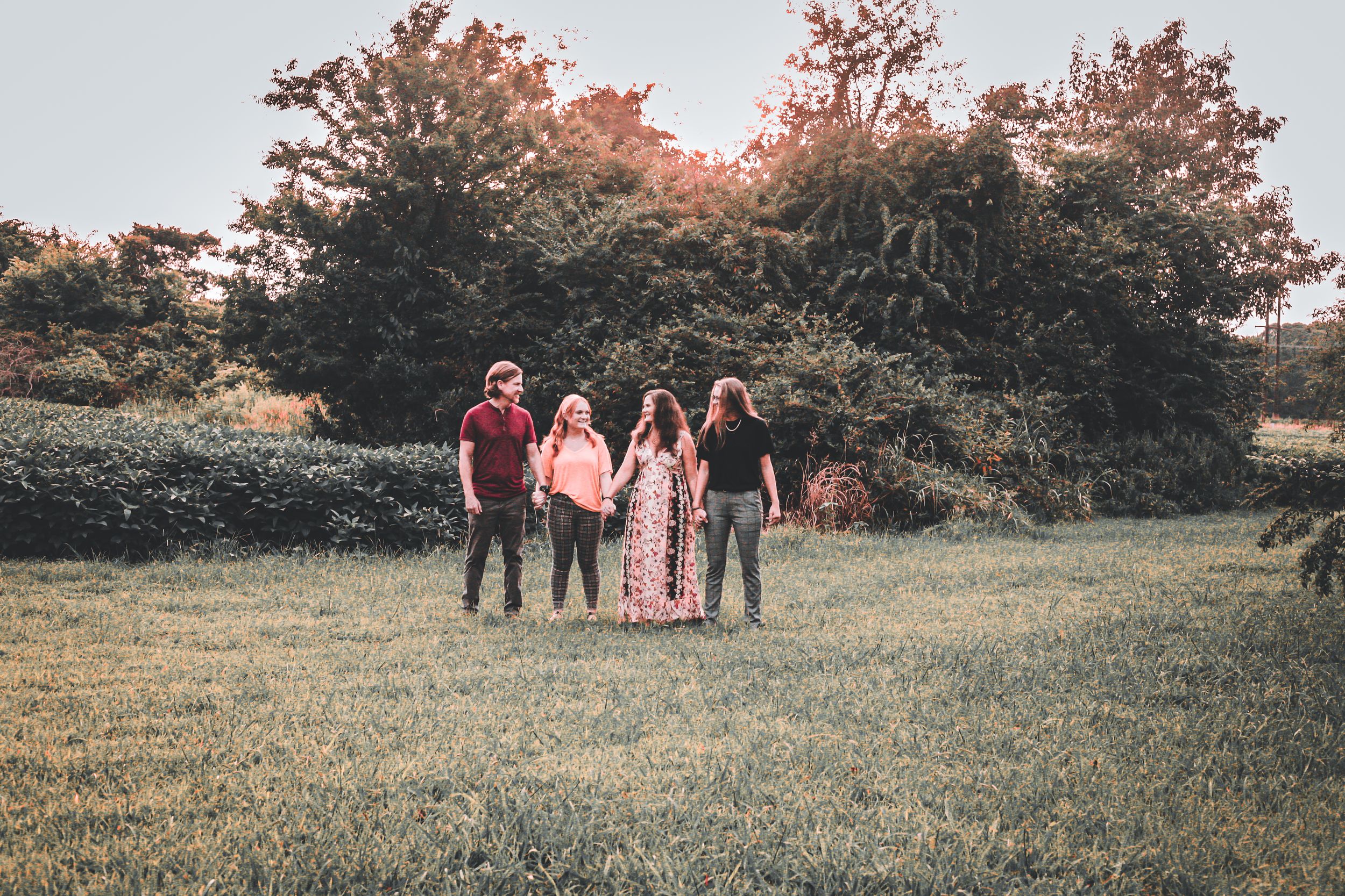 A small group stands together in a grassy field during golden hour.
