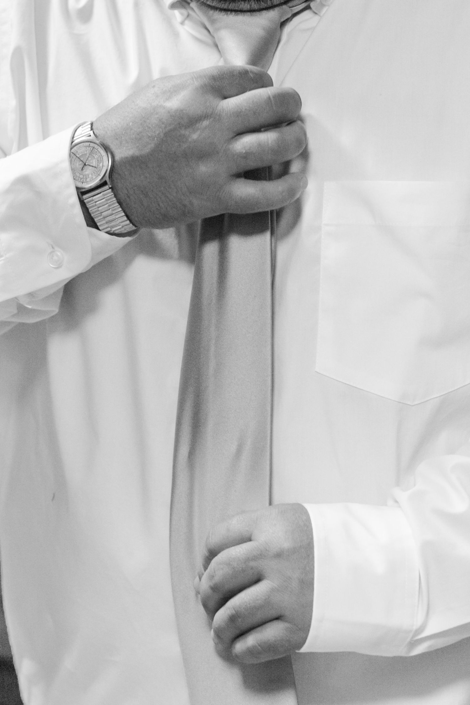 Close-up of formal white clothing being adjusted with careful hands.