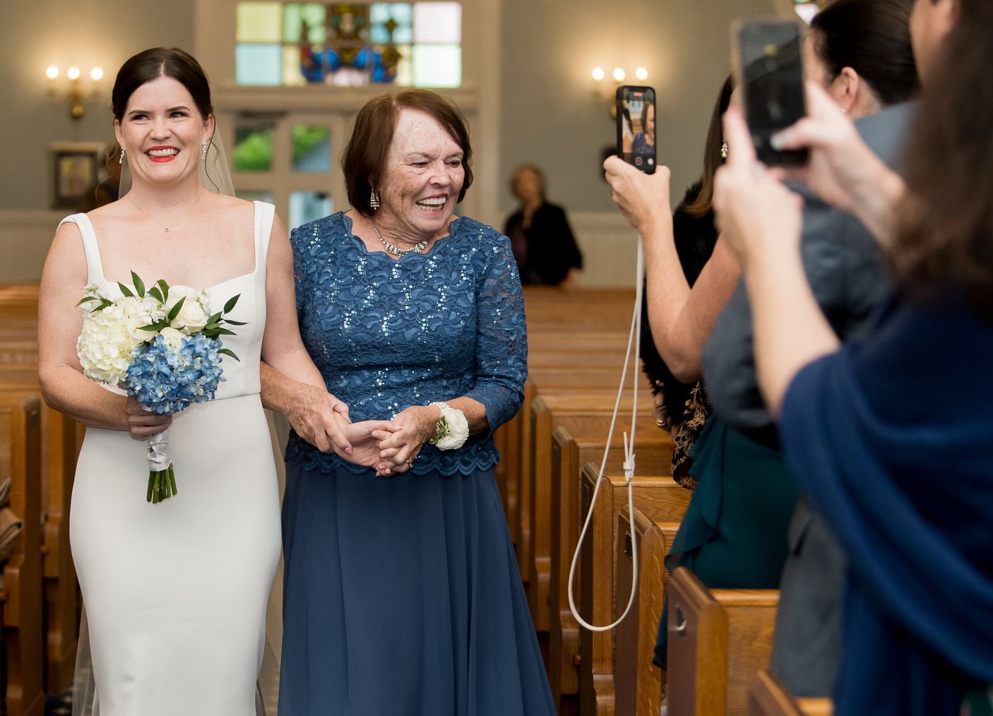 Wedding party in navy blue and white attire posing in a bright indoor venue.