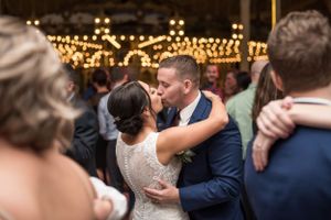 Wedding reception dance floor filled with couples under warm string lights.