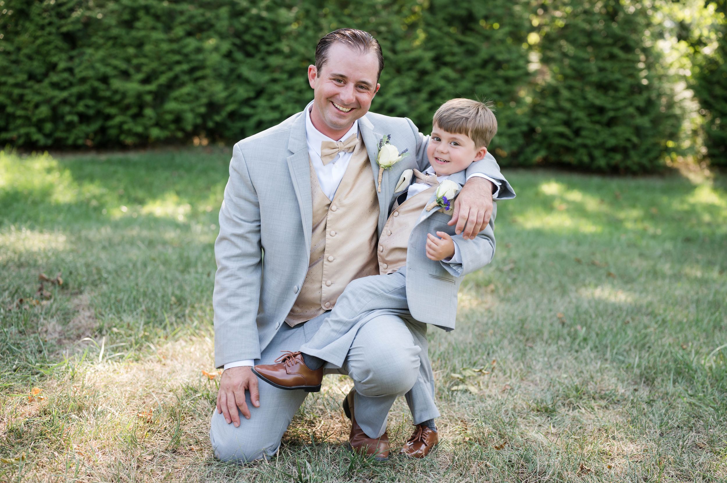 Wedding portraits in a sunny garden setting with grey suits and natural lighting.