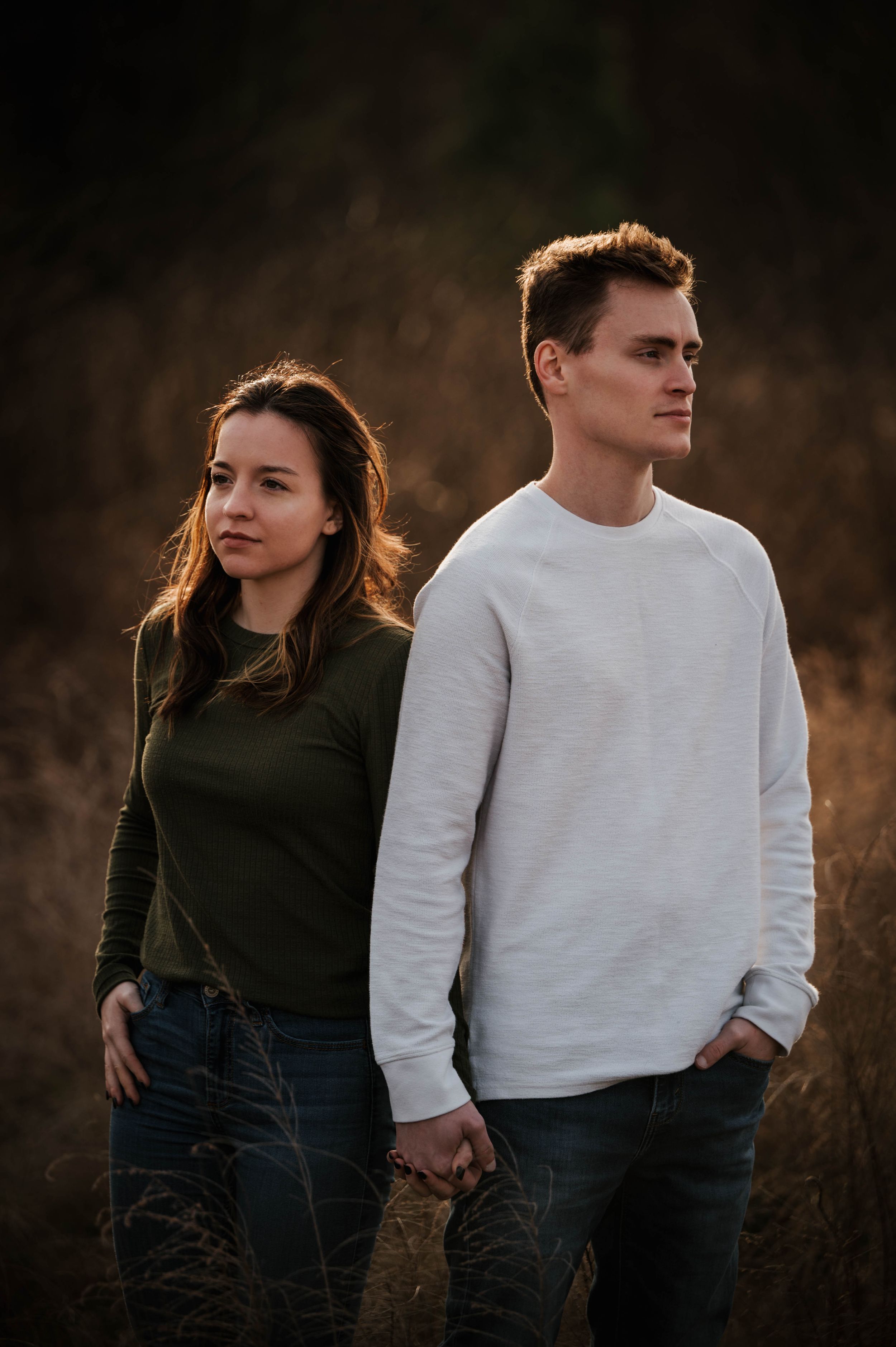 Artistic couples portrait session in field during golden hour.