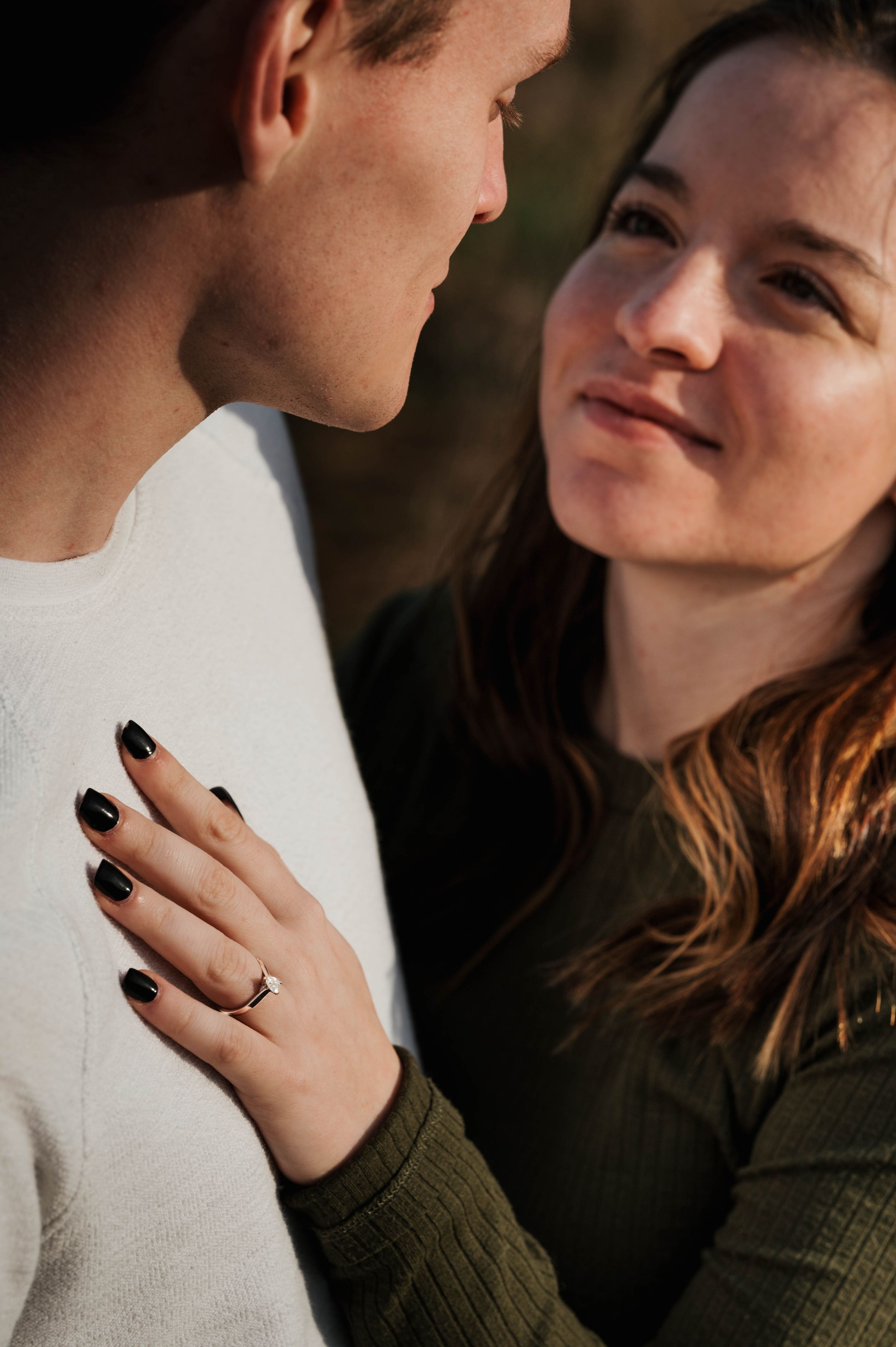 Close-up romantic portrait showing engagement ring and tender moment.