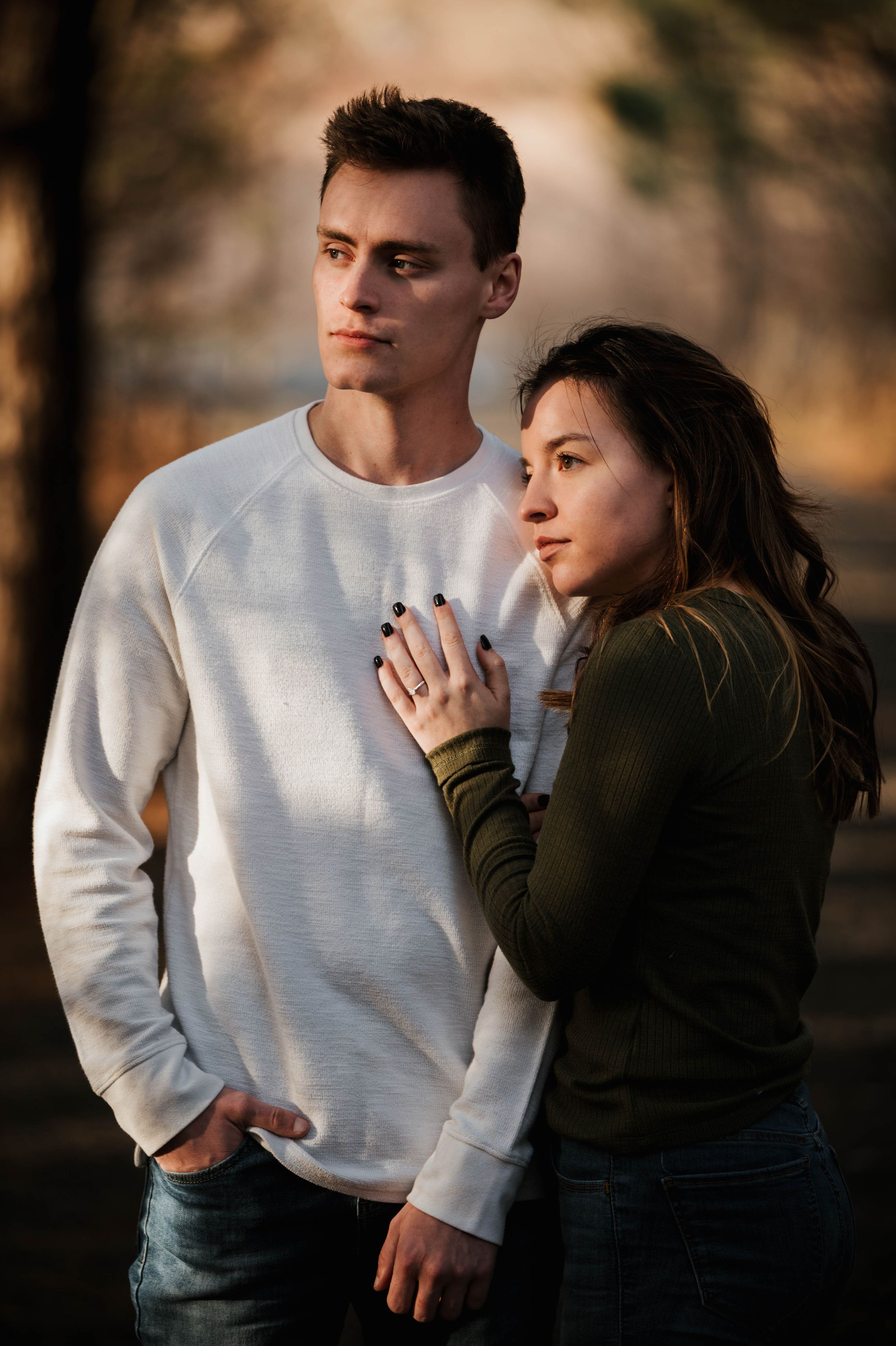 Intimate outdoor portrait of a couple in casual attire sharing a tender moment at sunset.