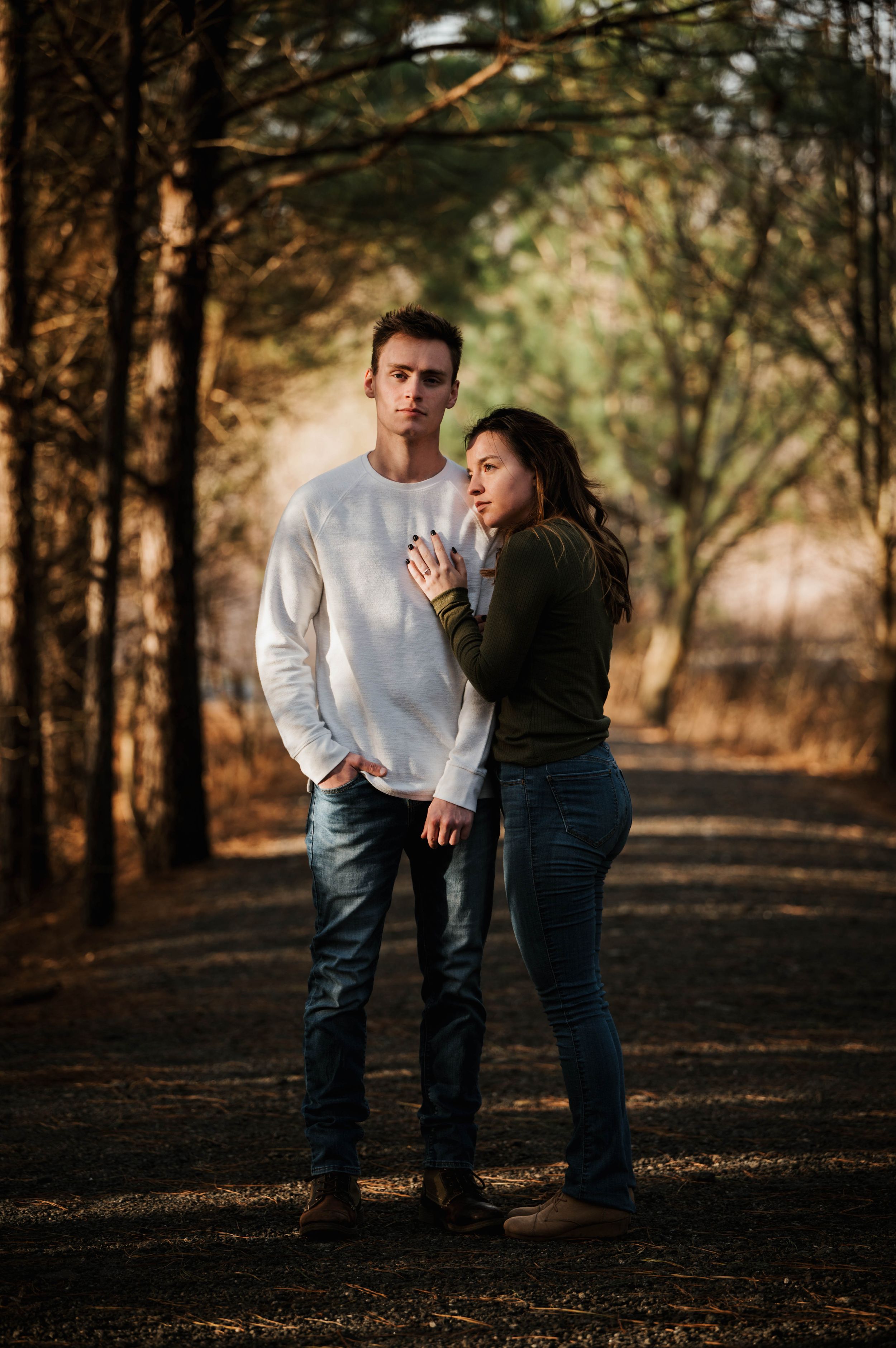 Romantic forest portrait of a couple in contrasting white and dark sweaters.