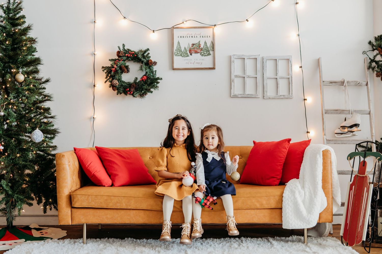 A cozy holiday living room with a tan leather sofa, Christmas tree, string lights and festive wreath on the wall at Grayscale Studios in JC