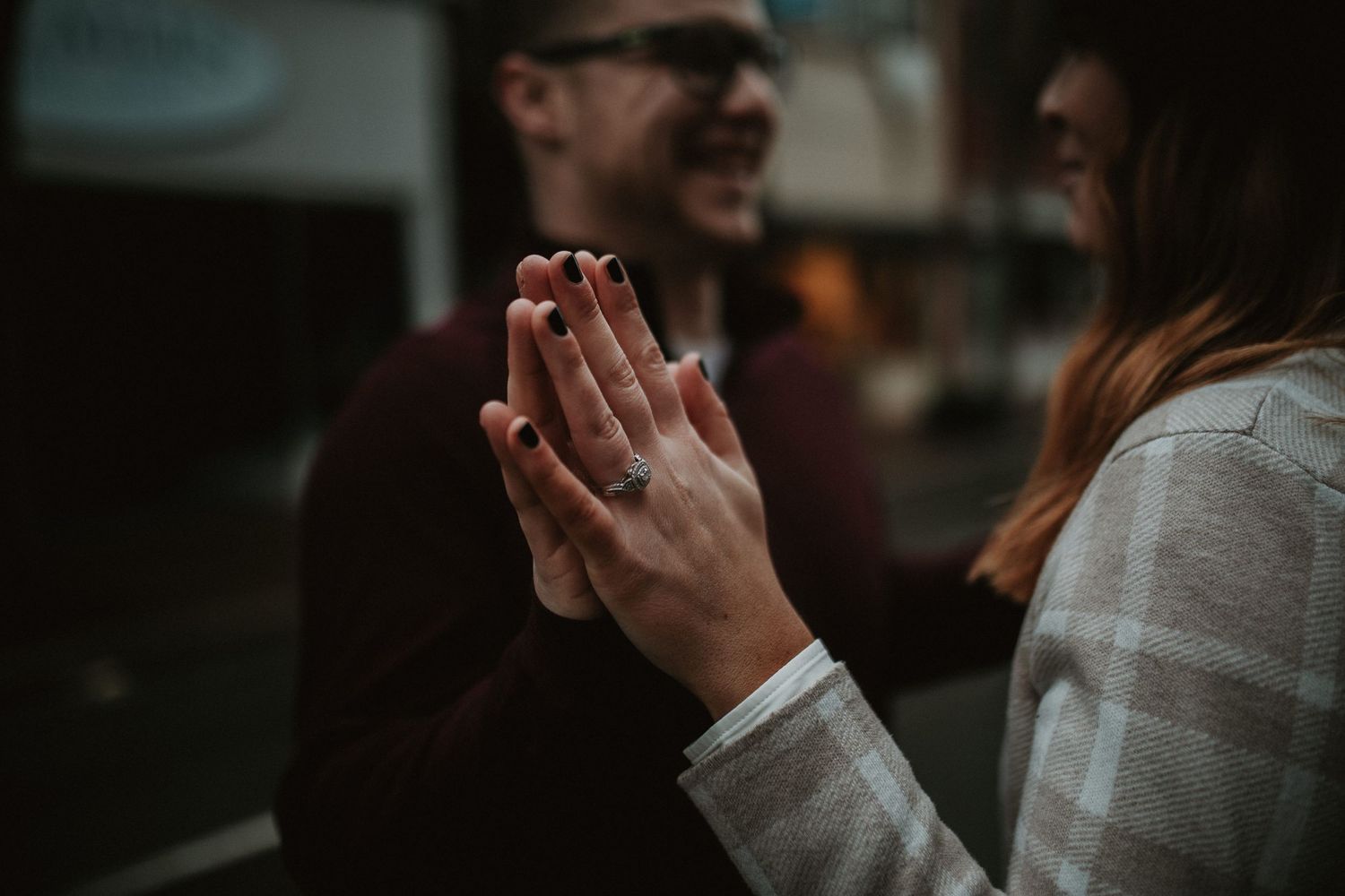 two people smiling at each other and engagement ring is in focus