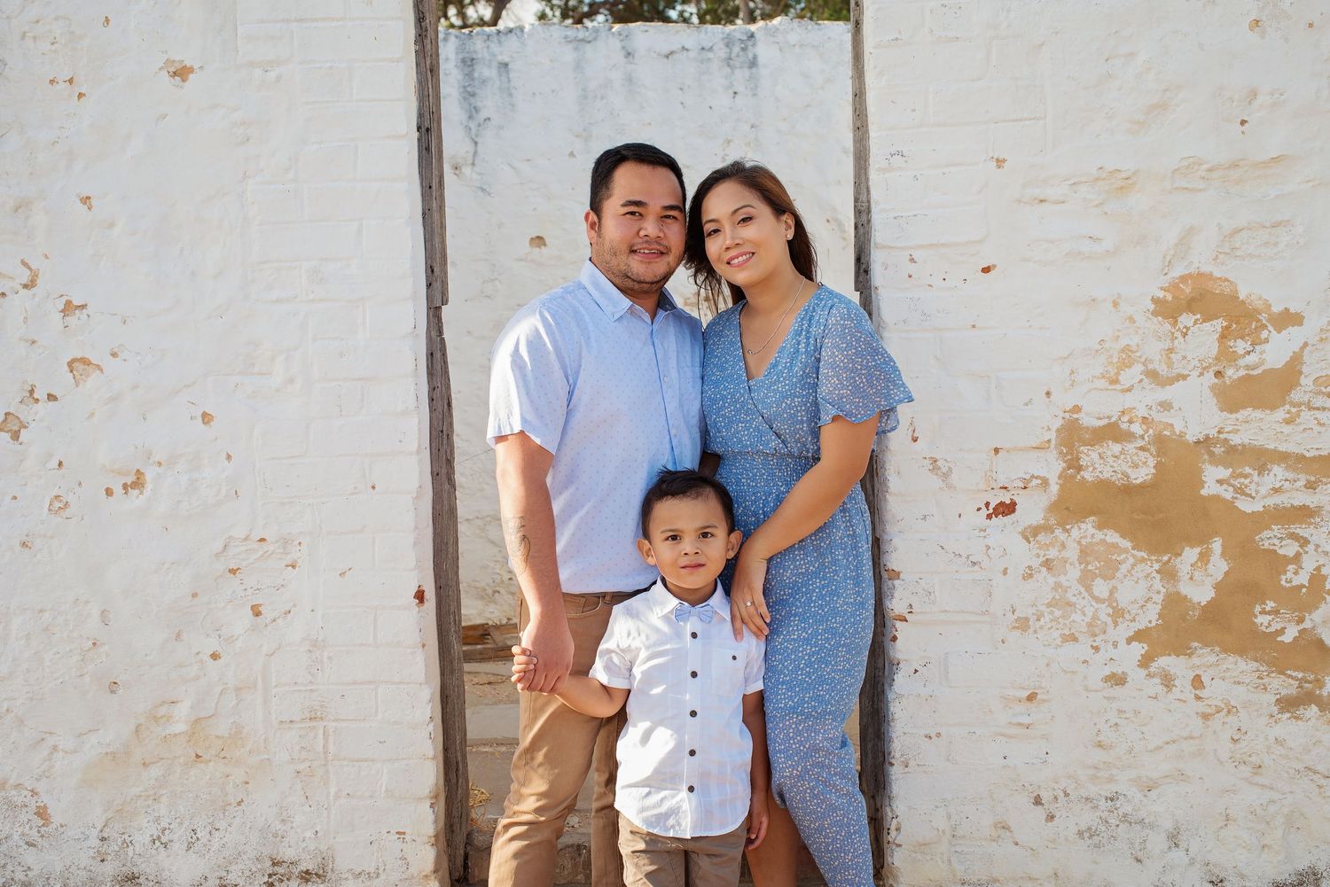 family posing infront of old doorway outside dressed in white and blue