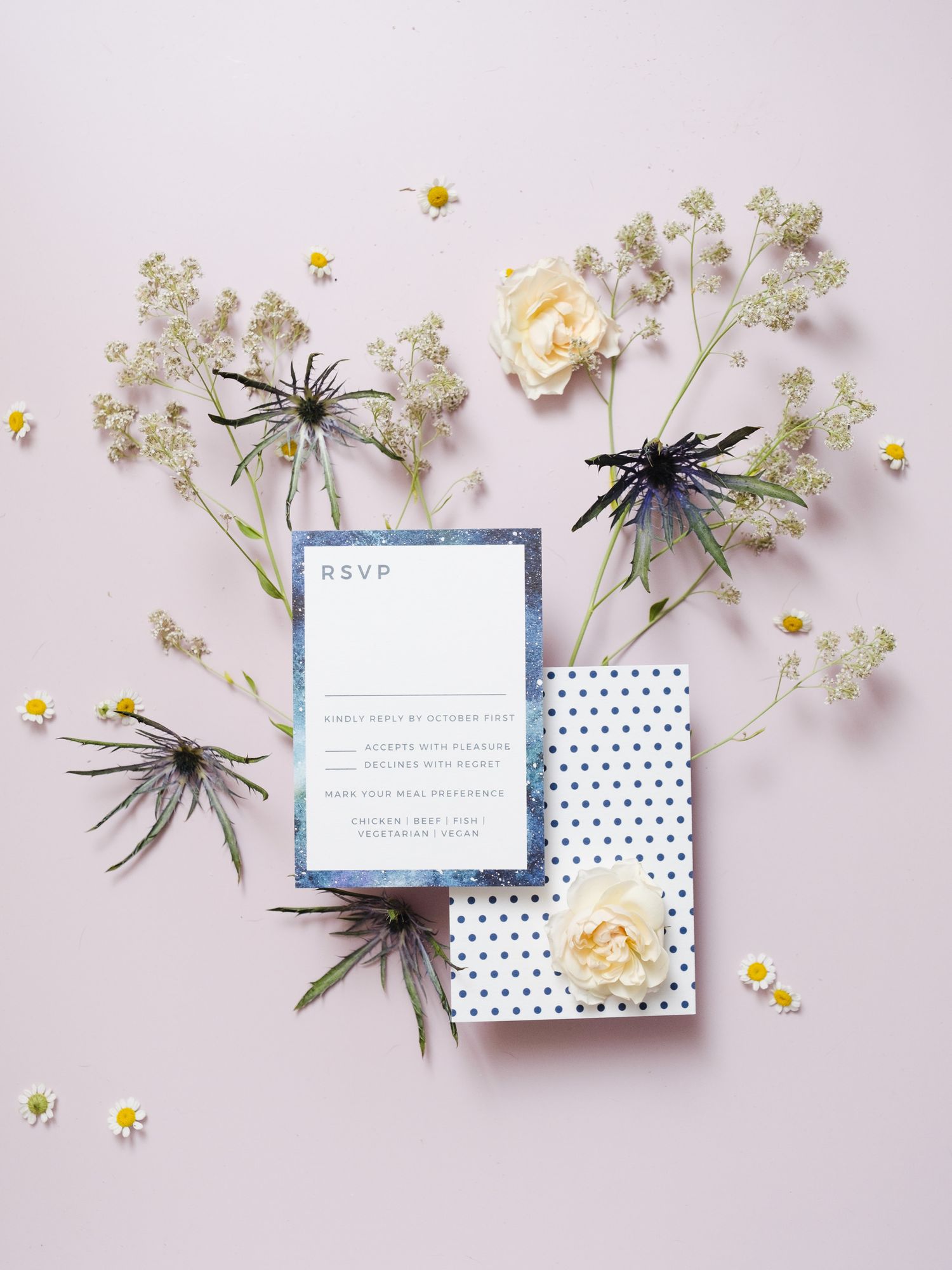 Wedding RSVP card with blue accents and polka dot design styled with white roses and delicate baby's breath flowers.
