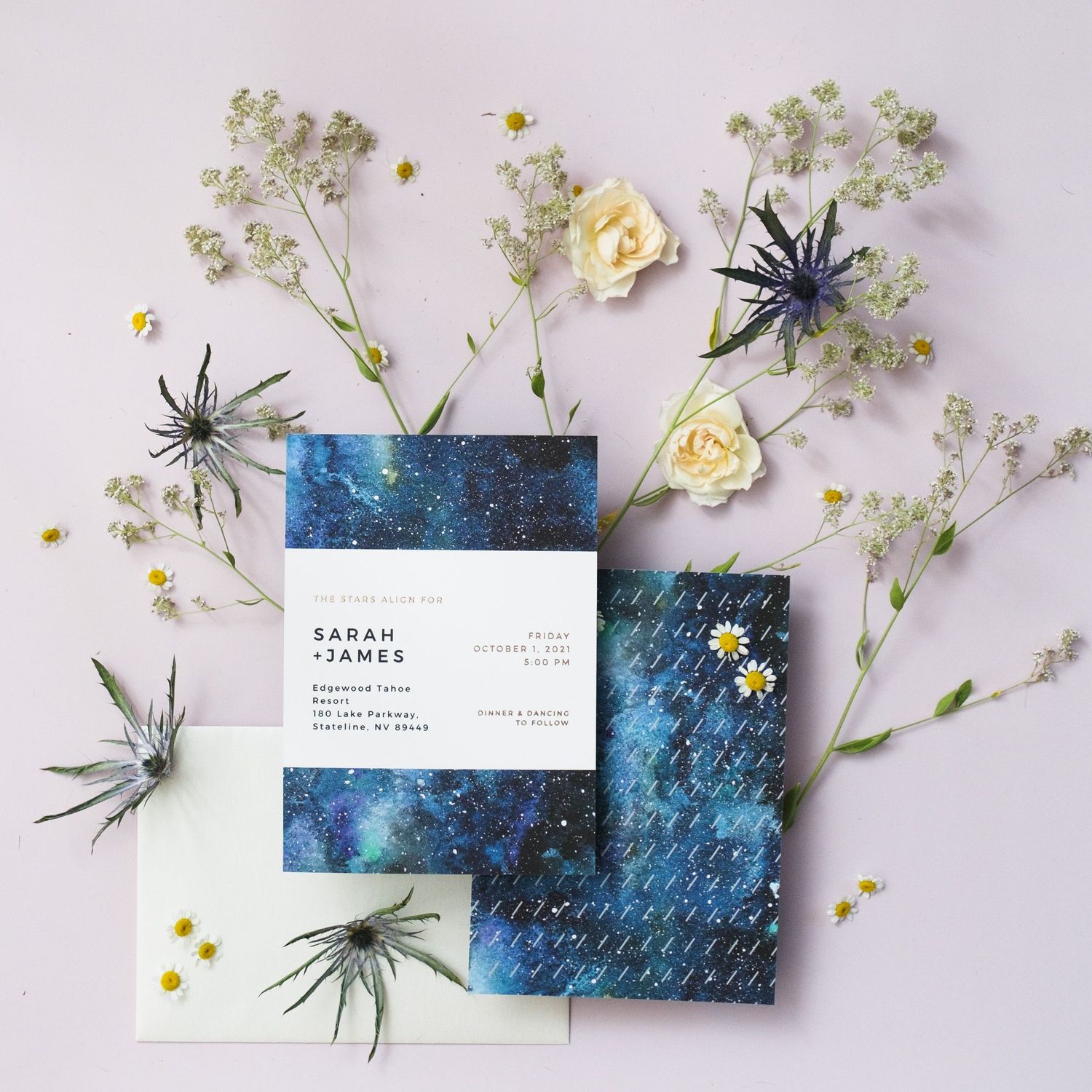Wedding stationery with blue watercolor design and dried flowers including baby's breath and small spiders for decoration.