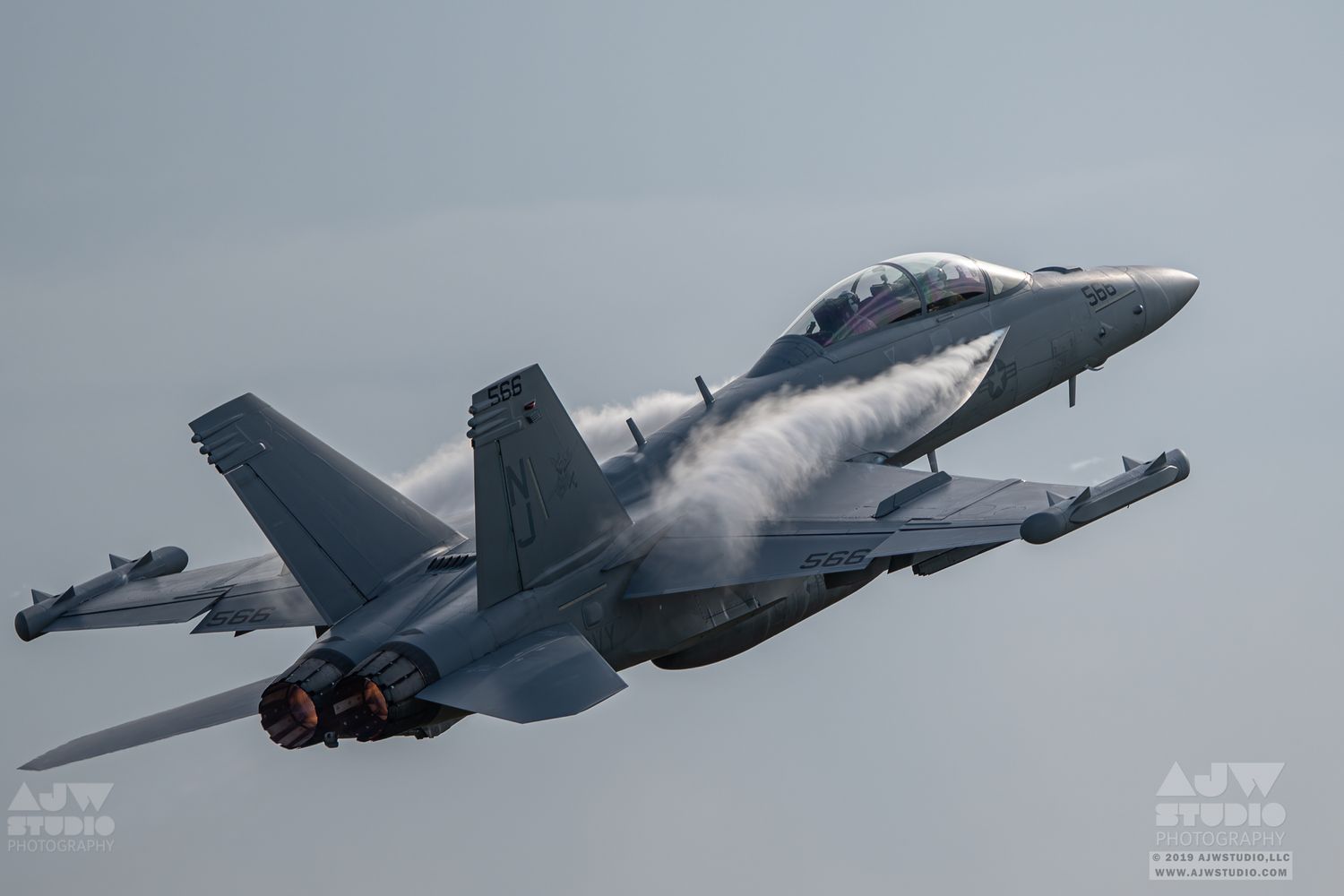 Military fighter jet aircraft in flight against cloudy sky.