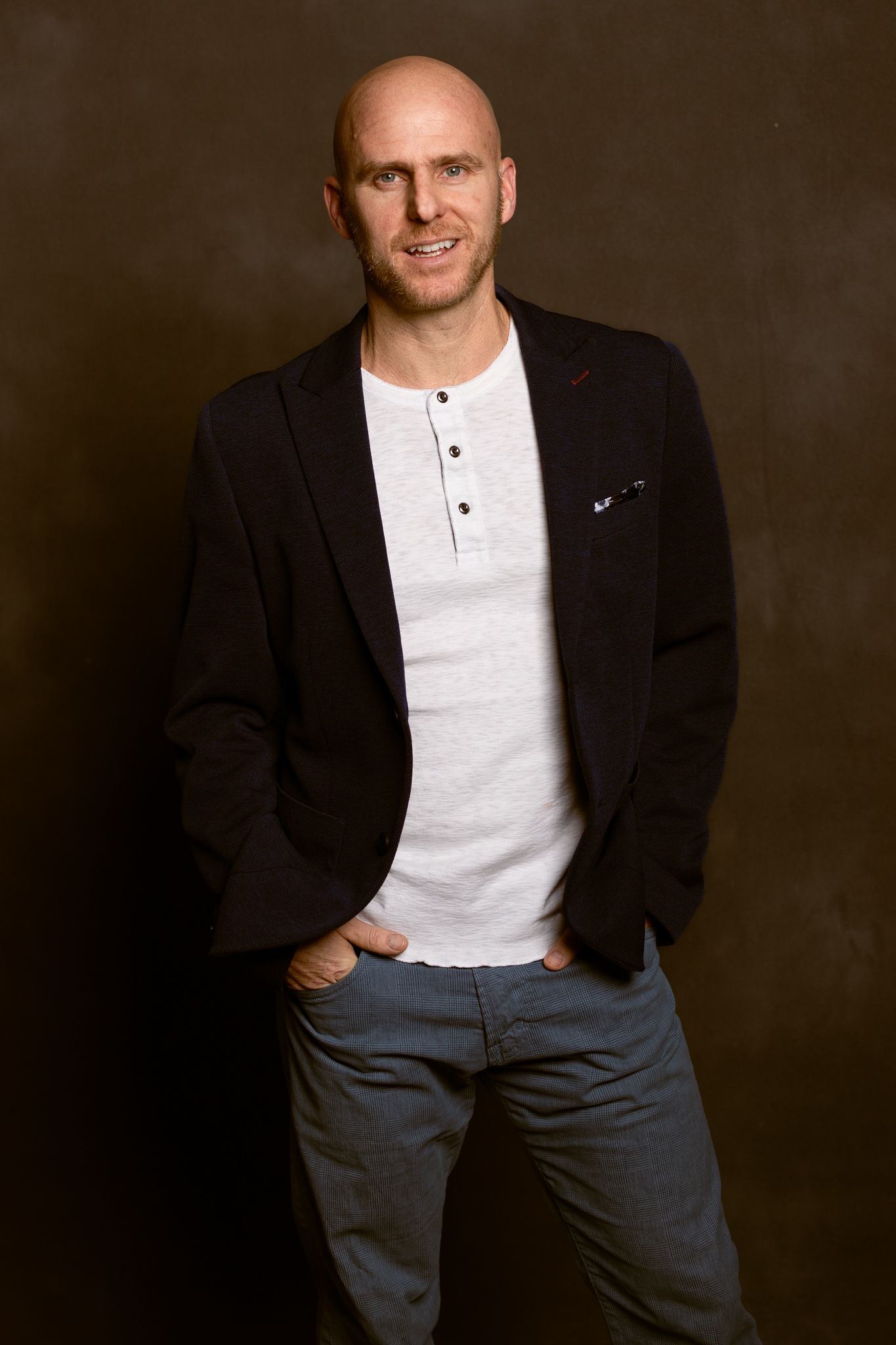 Professional portrait of person in casual business attire against dark background.