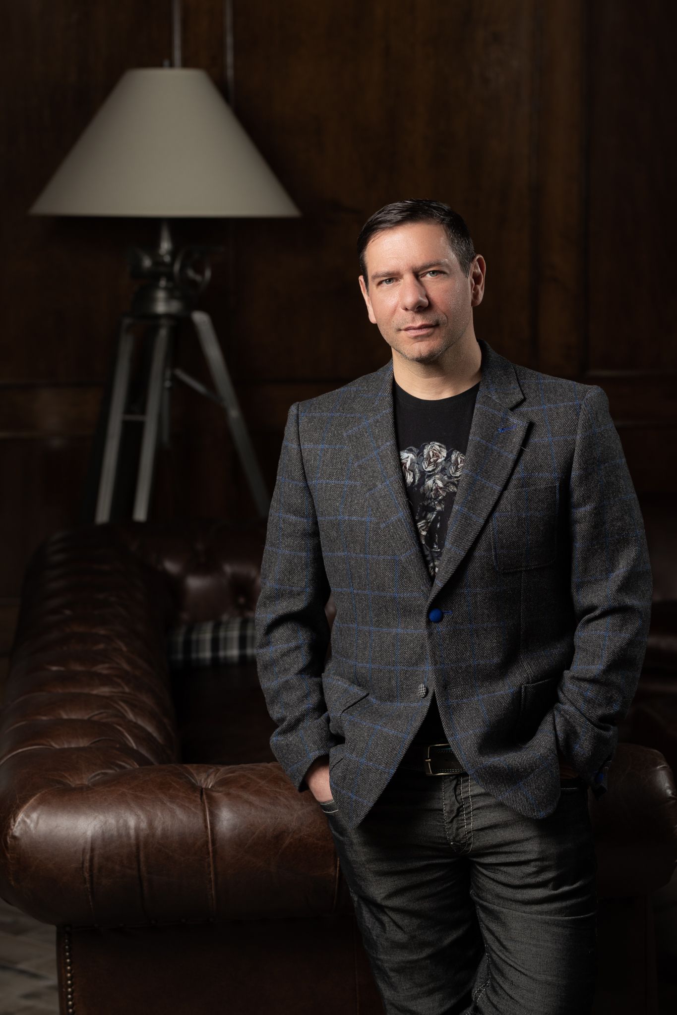 Professional portrait of person in gray suit jacket seated on leather couch.