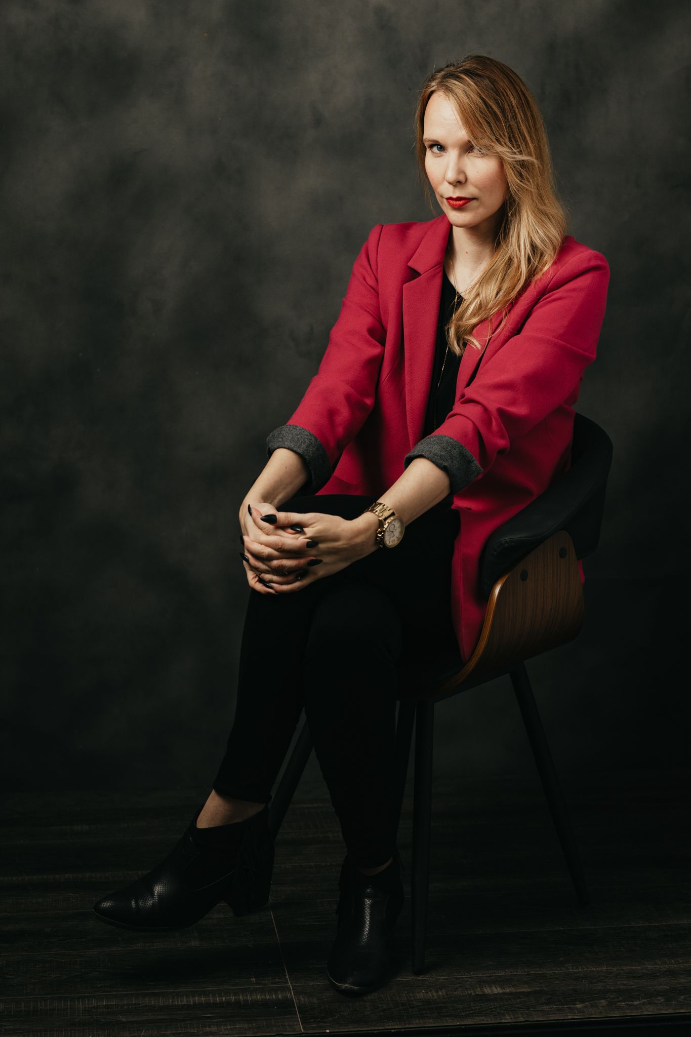 Dramatic portrait series featuring red blazer and black pants against dark studio backdrop.