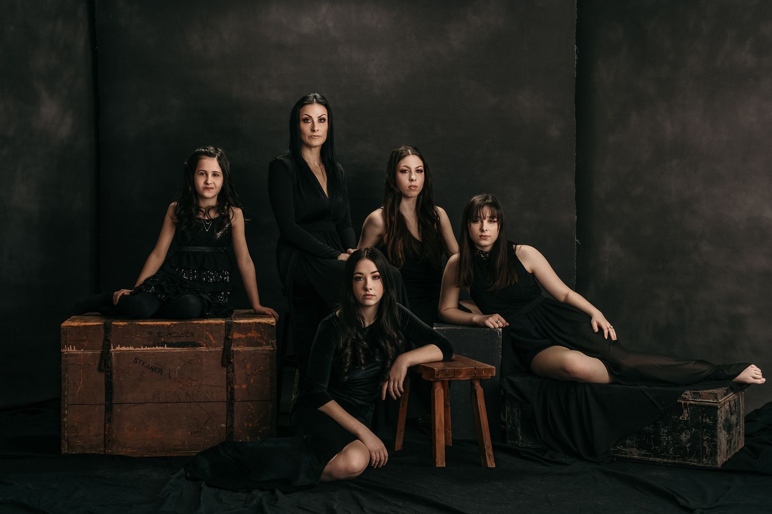 Artistic studio portraits with vintage wooden props against dark background.
