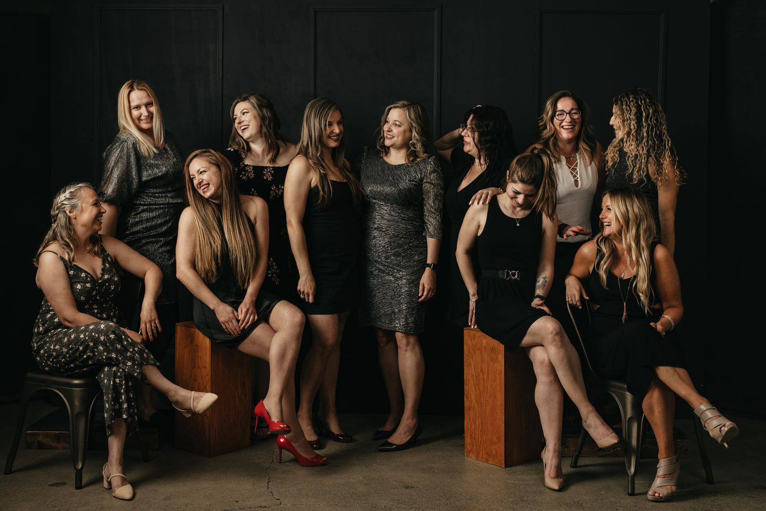 Group photo shoot with formal attire showing legs and shoes against dark backdrop.