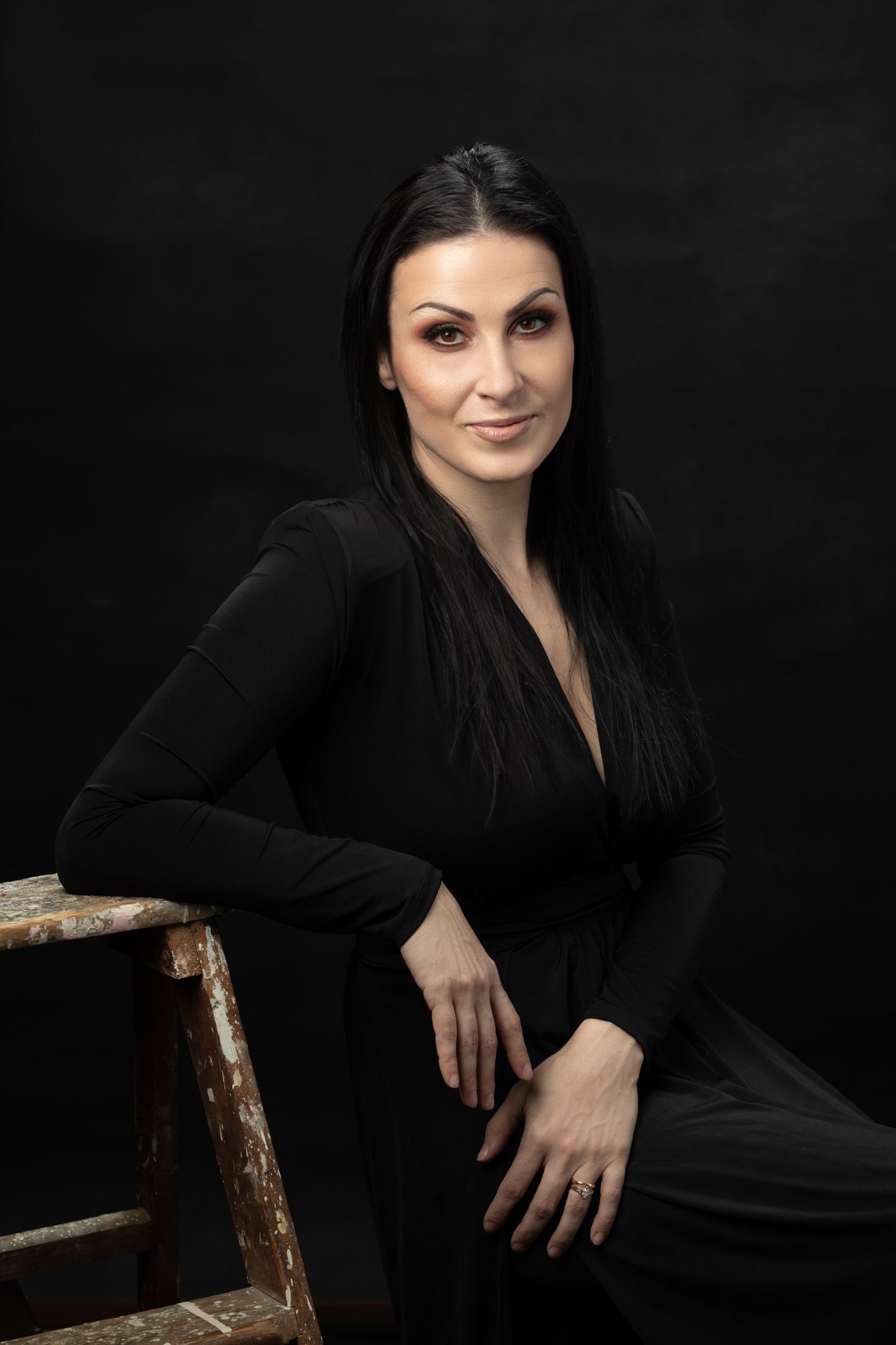 Elegant portrait series in black attire against dark background with dramatic lighting.