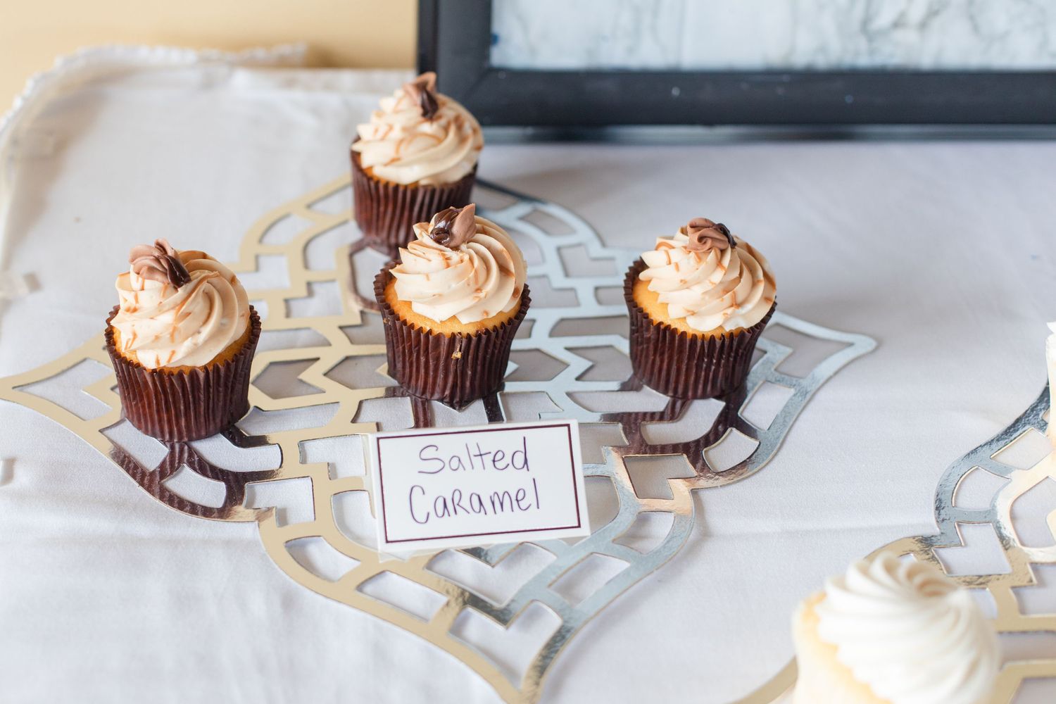 Row of chocolate cupcakes with swirled vanilla frosting arranged on white plates.
