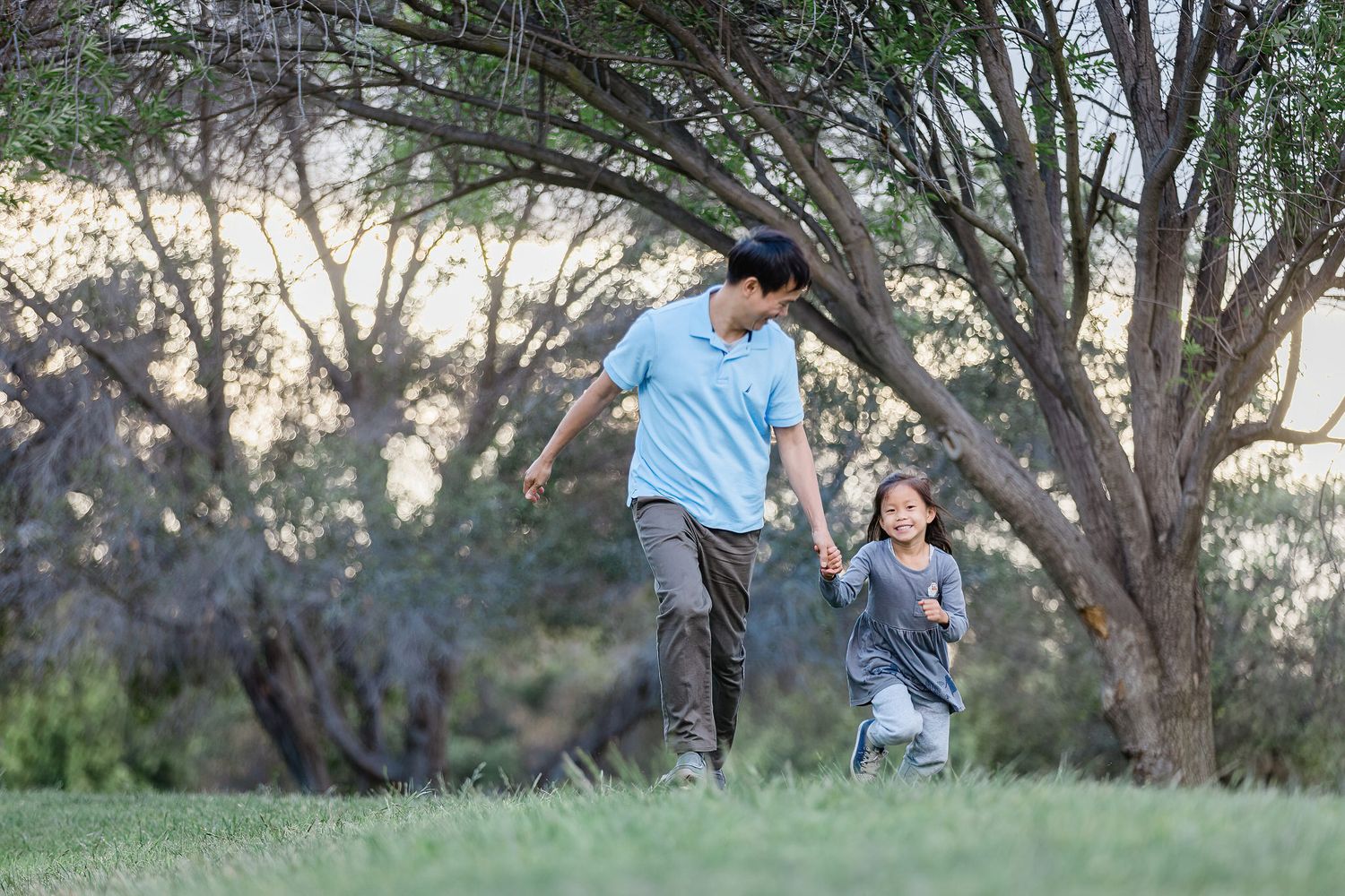 Two people running and playing together joyfully in a park at sunset.