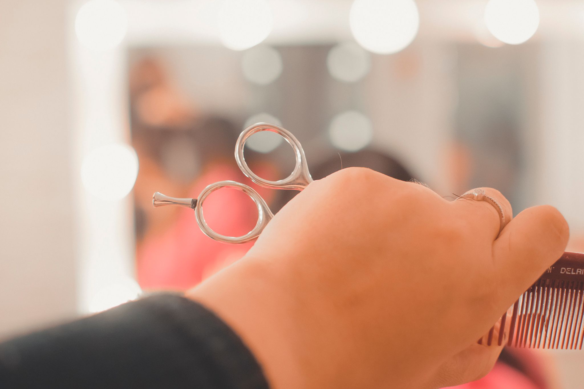 Close up of hairdressing scissors held by stylist's hand against blurred background.