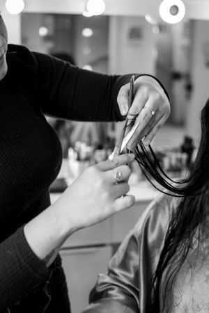 Close-up black and white shot of hands cutting hair with professional scissors.