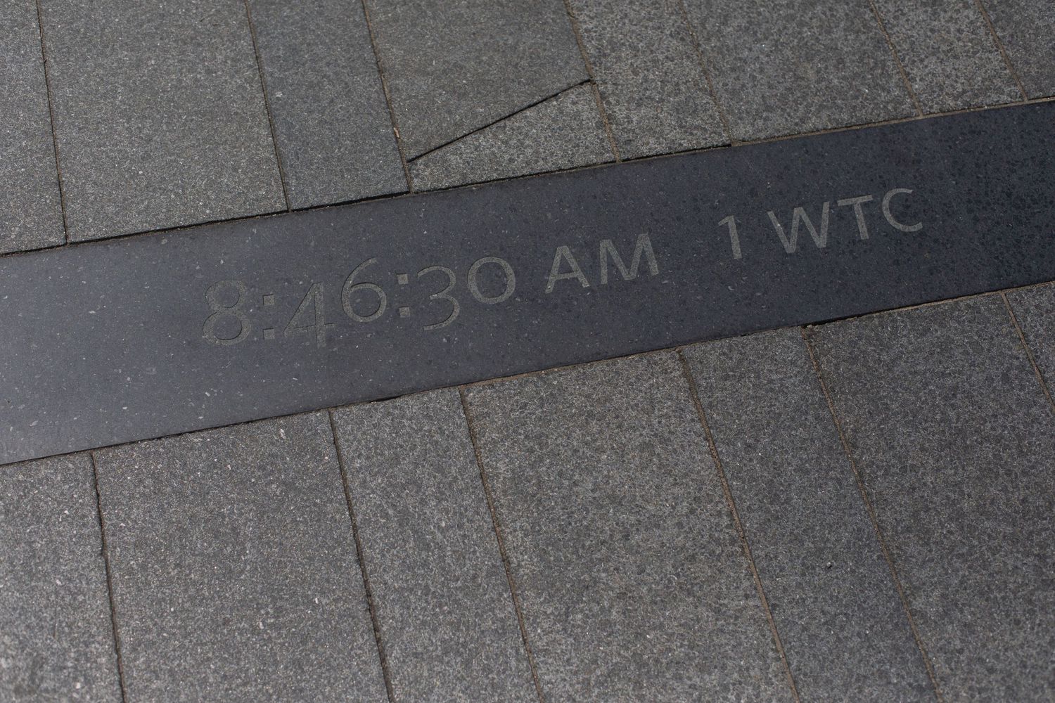 Stone inscription marking World Trade Center attack time in memorial.