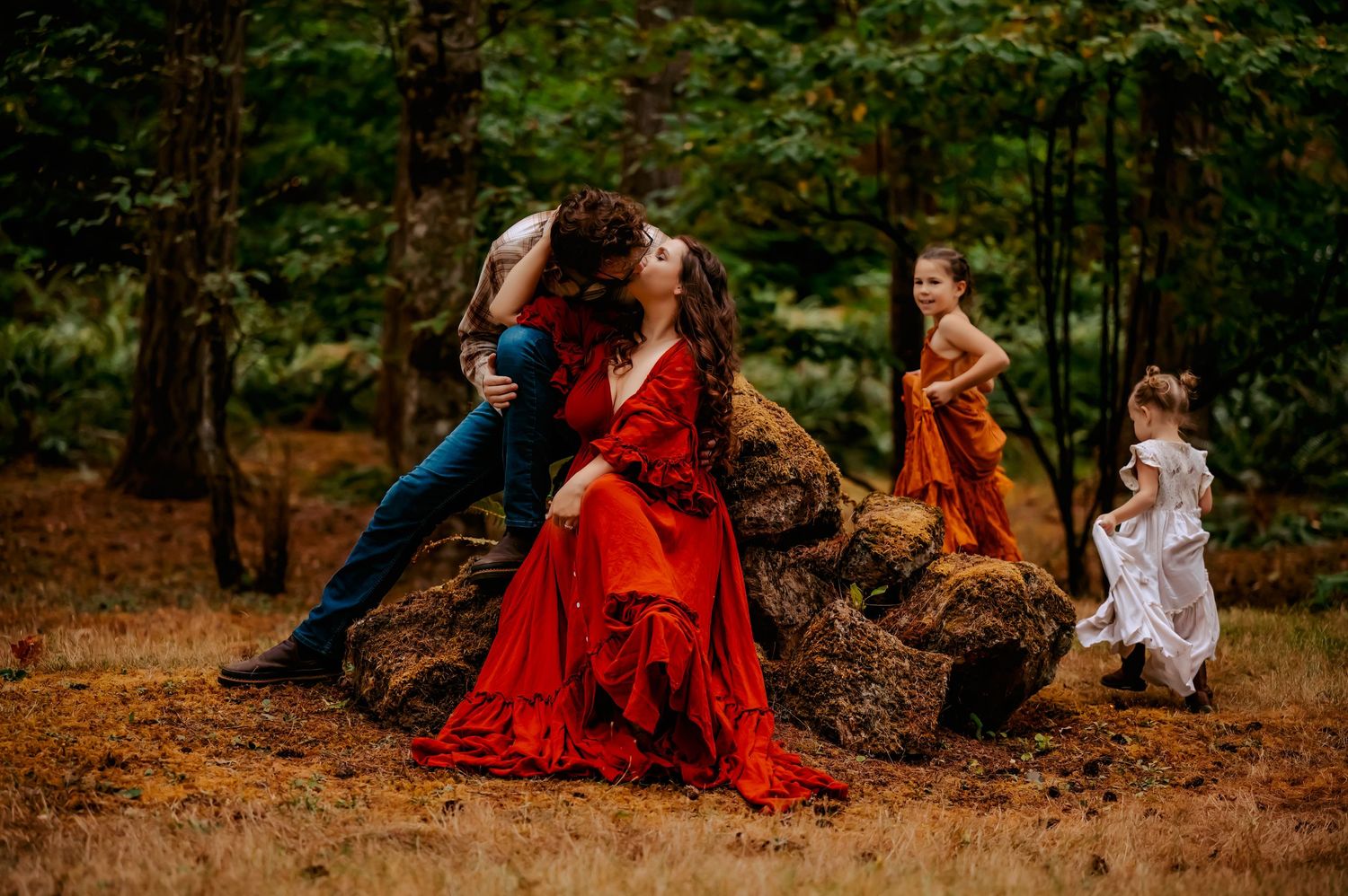Artistic outdoor family photo session with red and white dresses in forest setting.