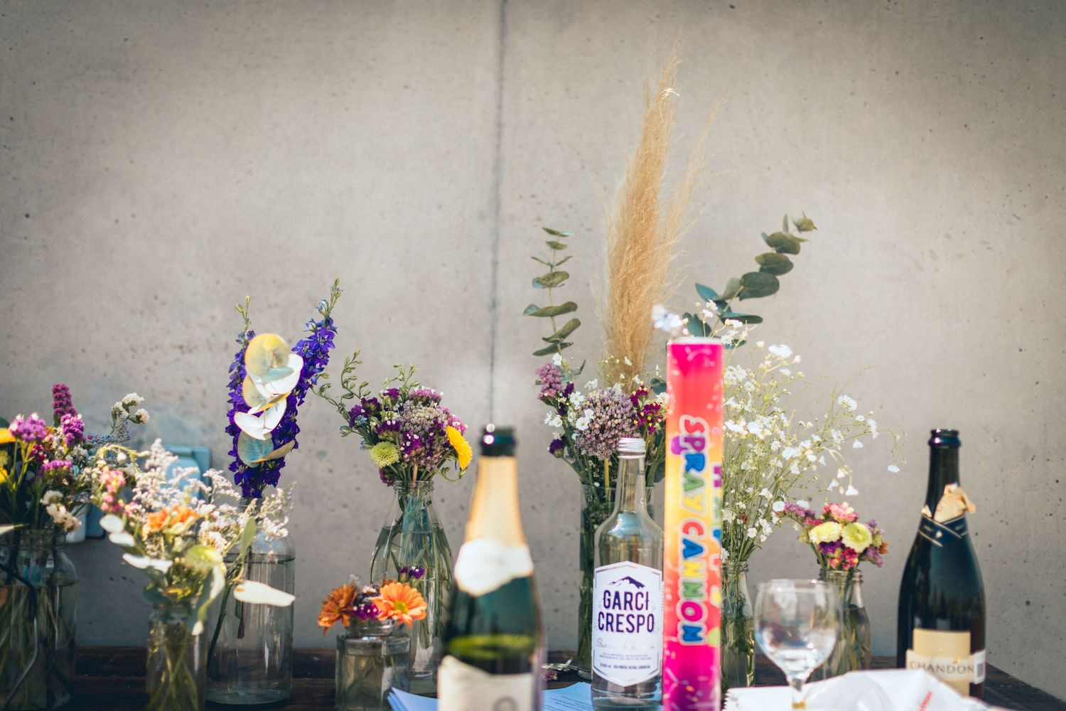 Elegant floral arrangements and vases displayed on a gray surface with delicate dried flowers.